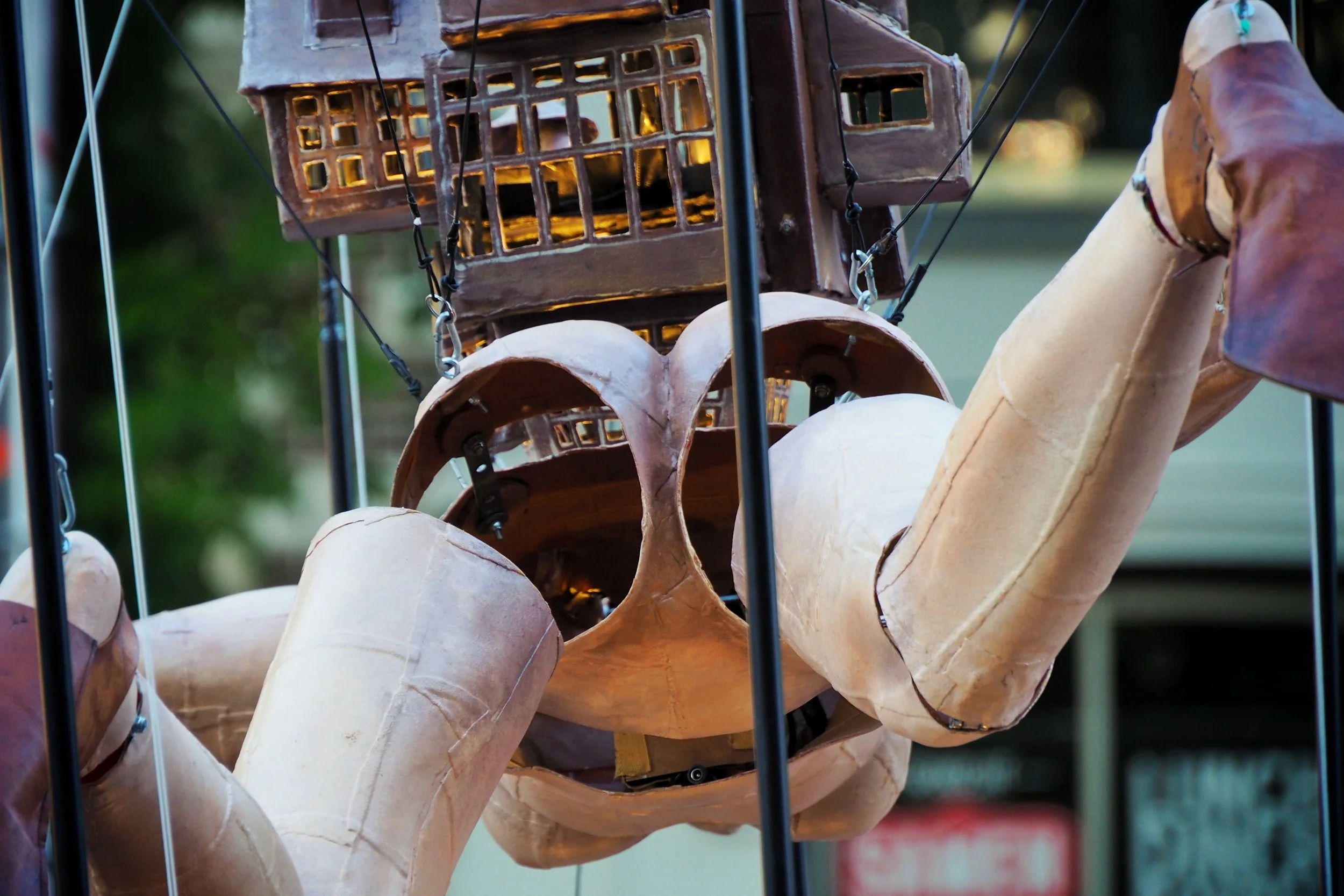 A close-up of lanterns made from carved and painted gourds hanging from a metal frame outdoors.