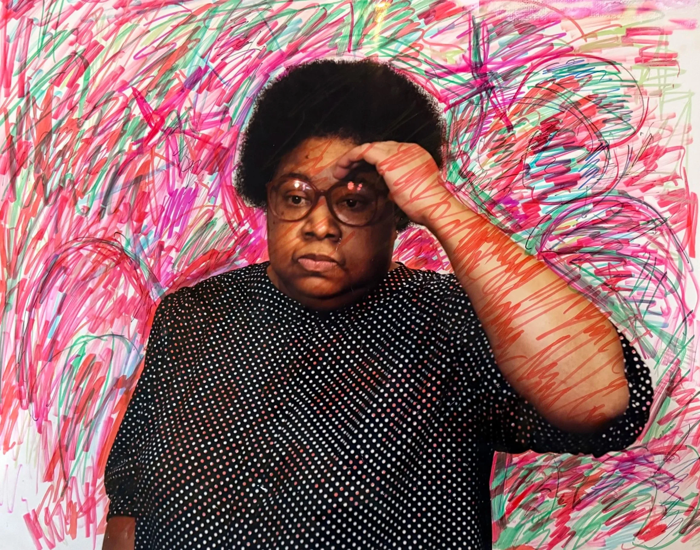 Beverly Buchanan photo, self-portrait, drawing on photo. A woman with short curly hair and glasses, wearing a black shirt with white dots, abstract scribbles in pink, green, red, and blue,.