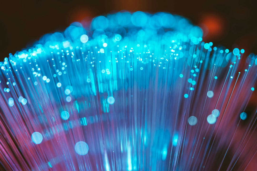 Close-up of illuminated fiber optic cables emitting blue and purple light.
