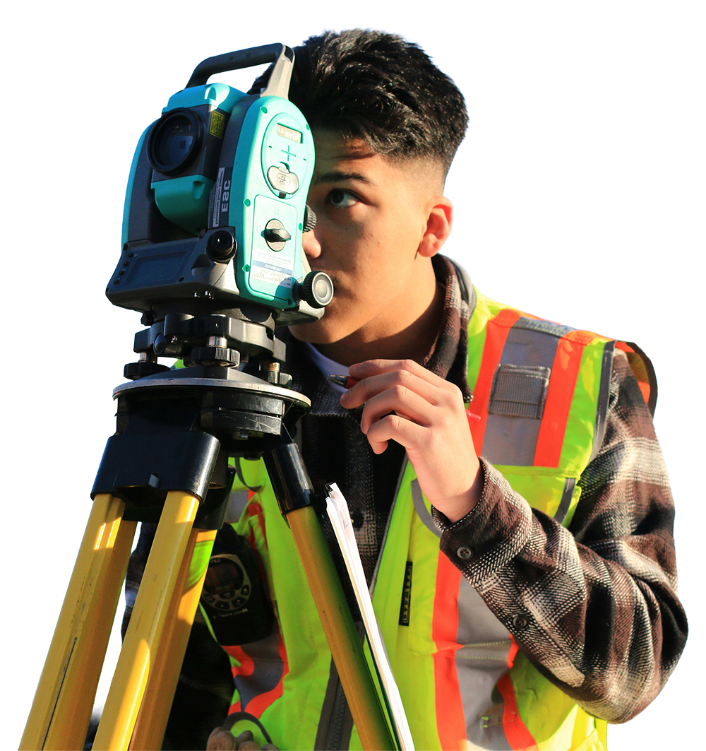 A young man using a theodolite or surveying instrument on a tripod, wearing a work vest with safety reflective stripes.