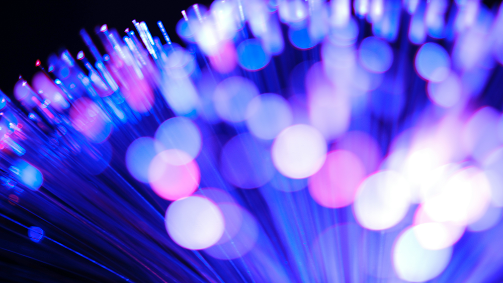 Close-up of fiber optic cables emitting blue and purple light.