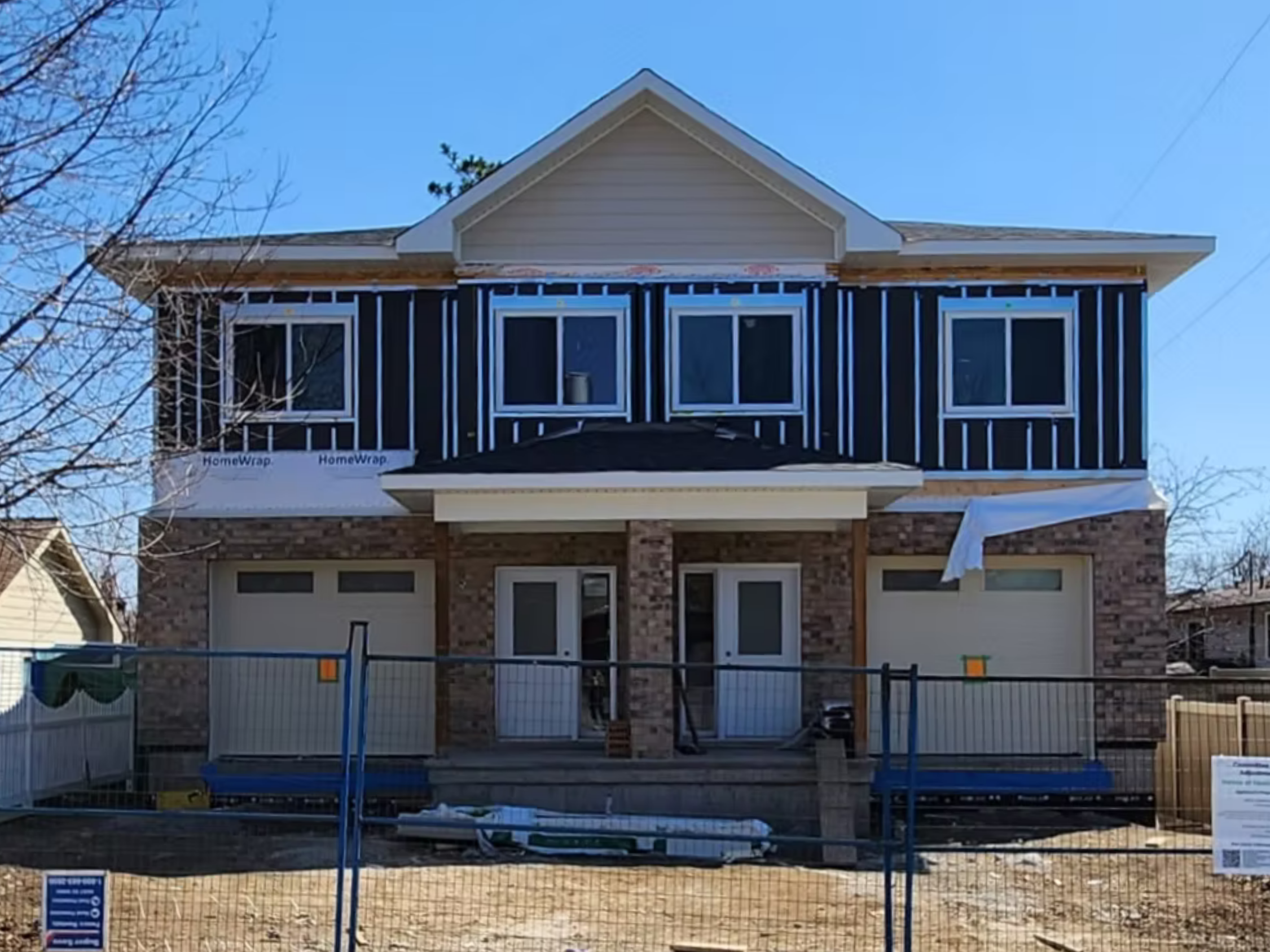 A front side exterior image of an urband duplex build called "St Stephen's" with two doors and two garages with a sunny sky.