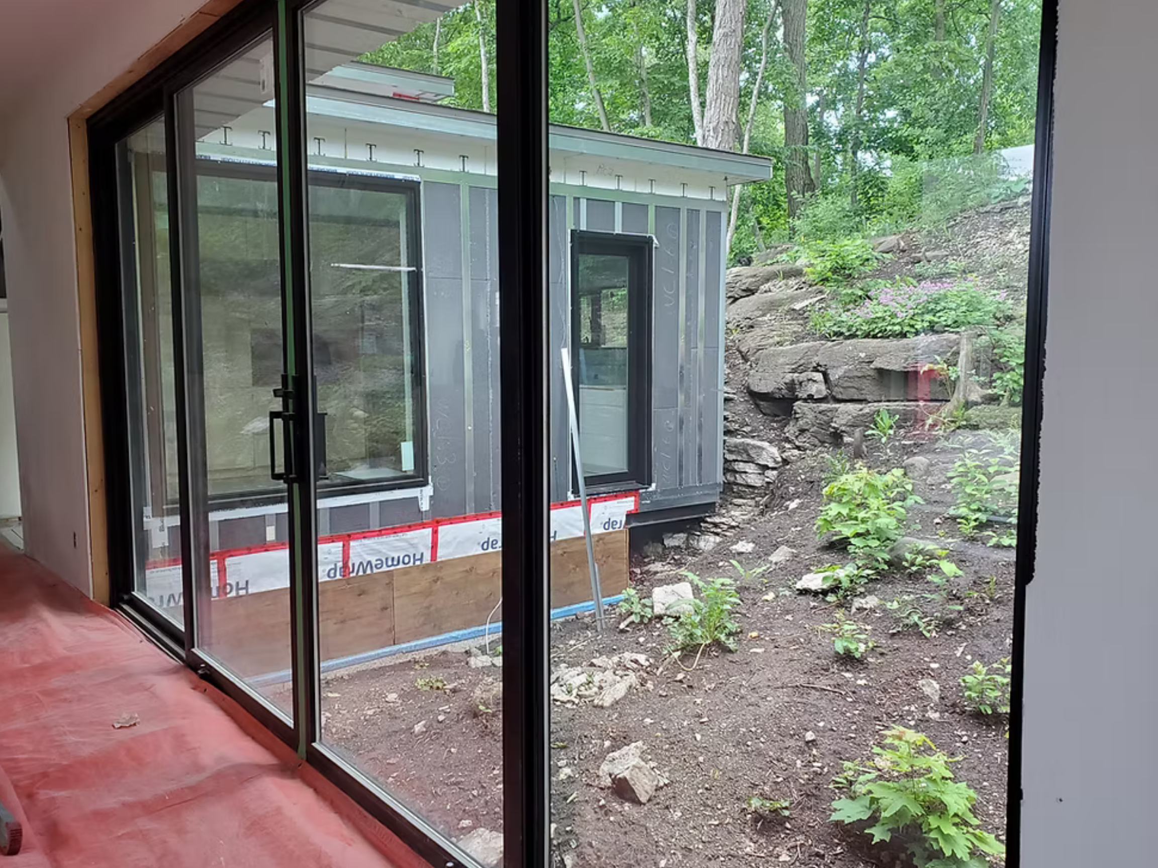 Exterior and interior image of the "Rothhwell", a custom residence with the HARMONIC building envelope and large windows and a sliding glass door.