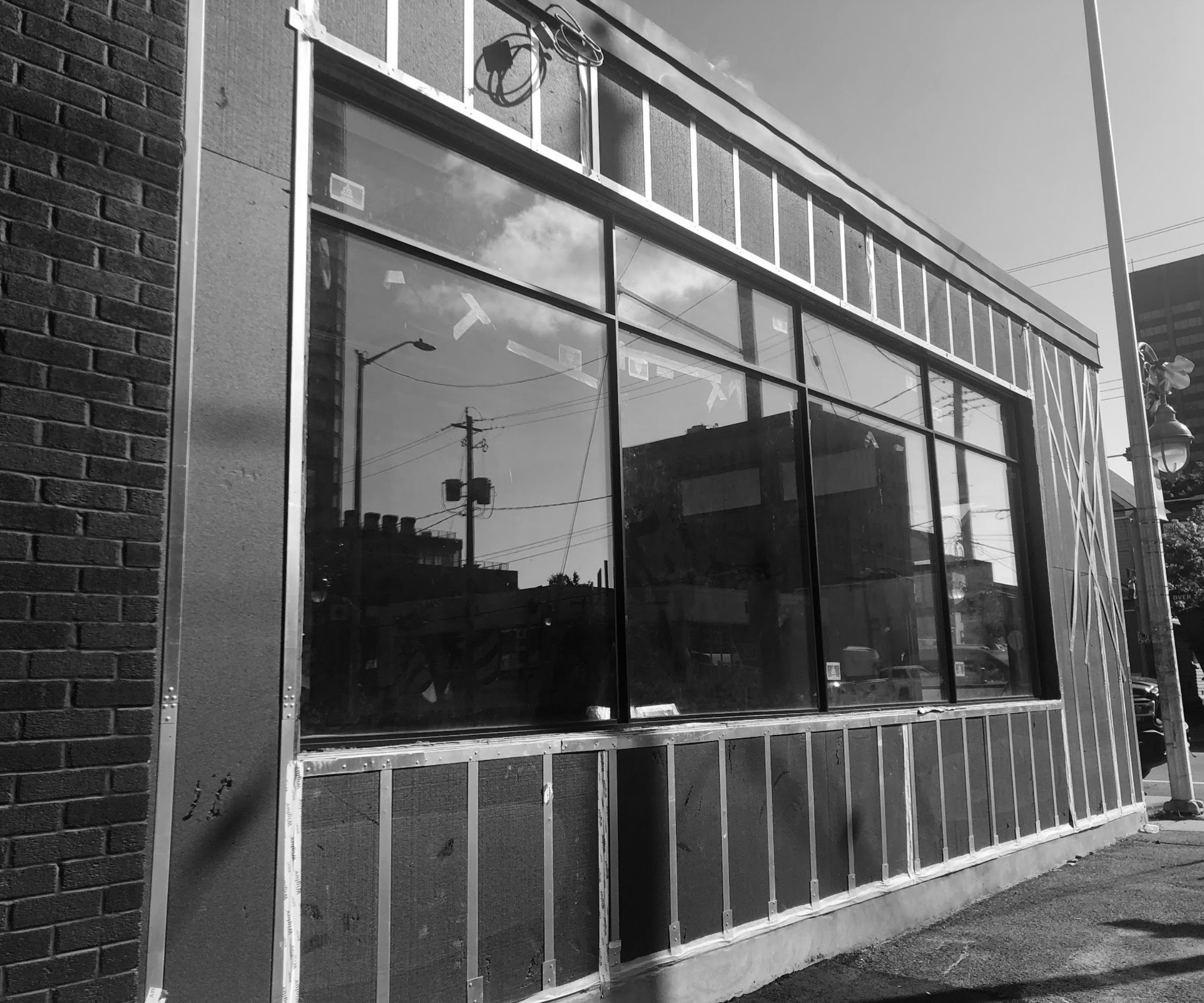A black and white image of a multi-family home exterior croppped in with a fence. 