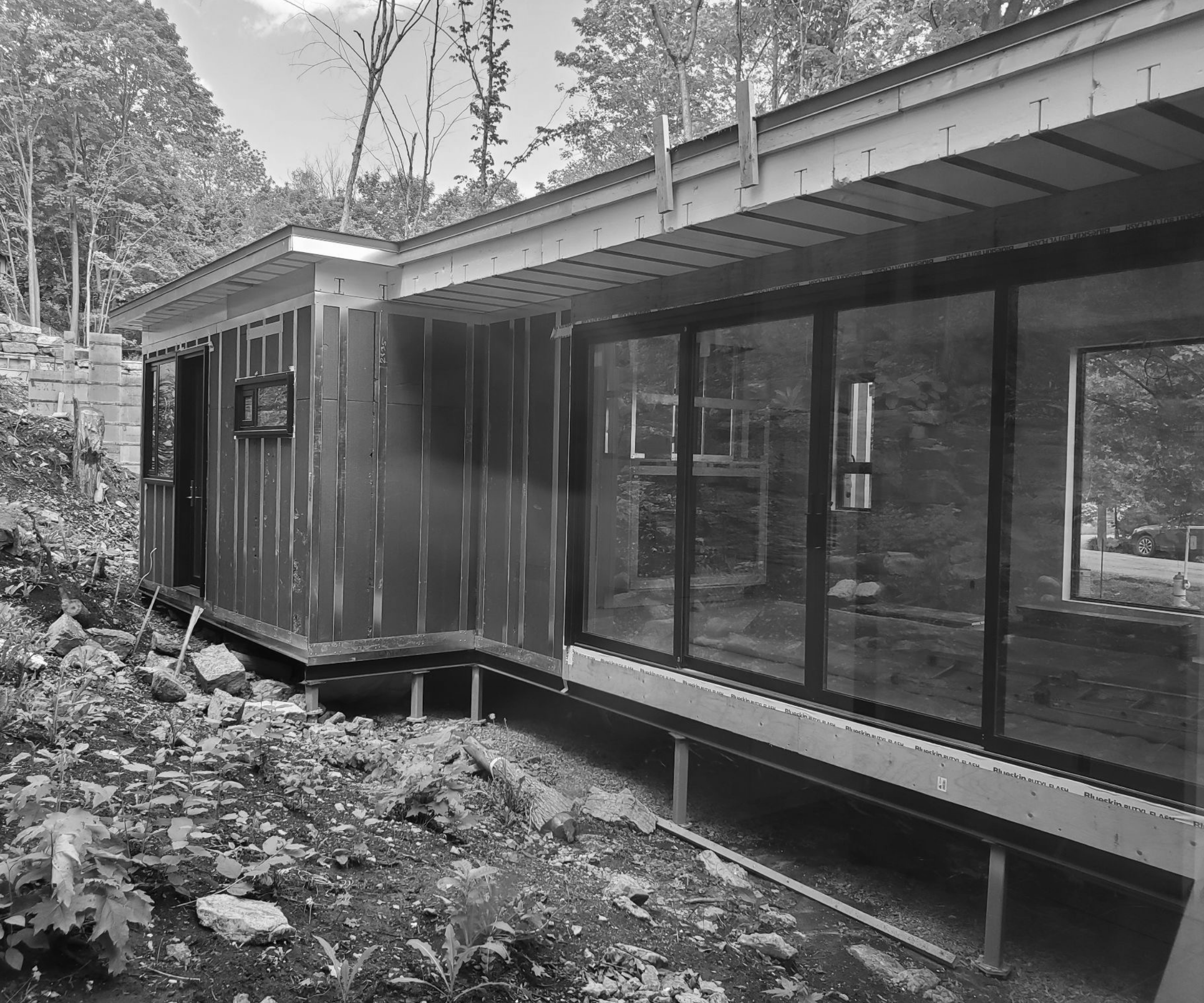 A black and white rendering of a single family home exterior with large windows. 