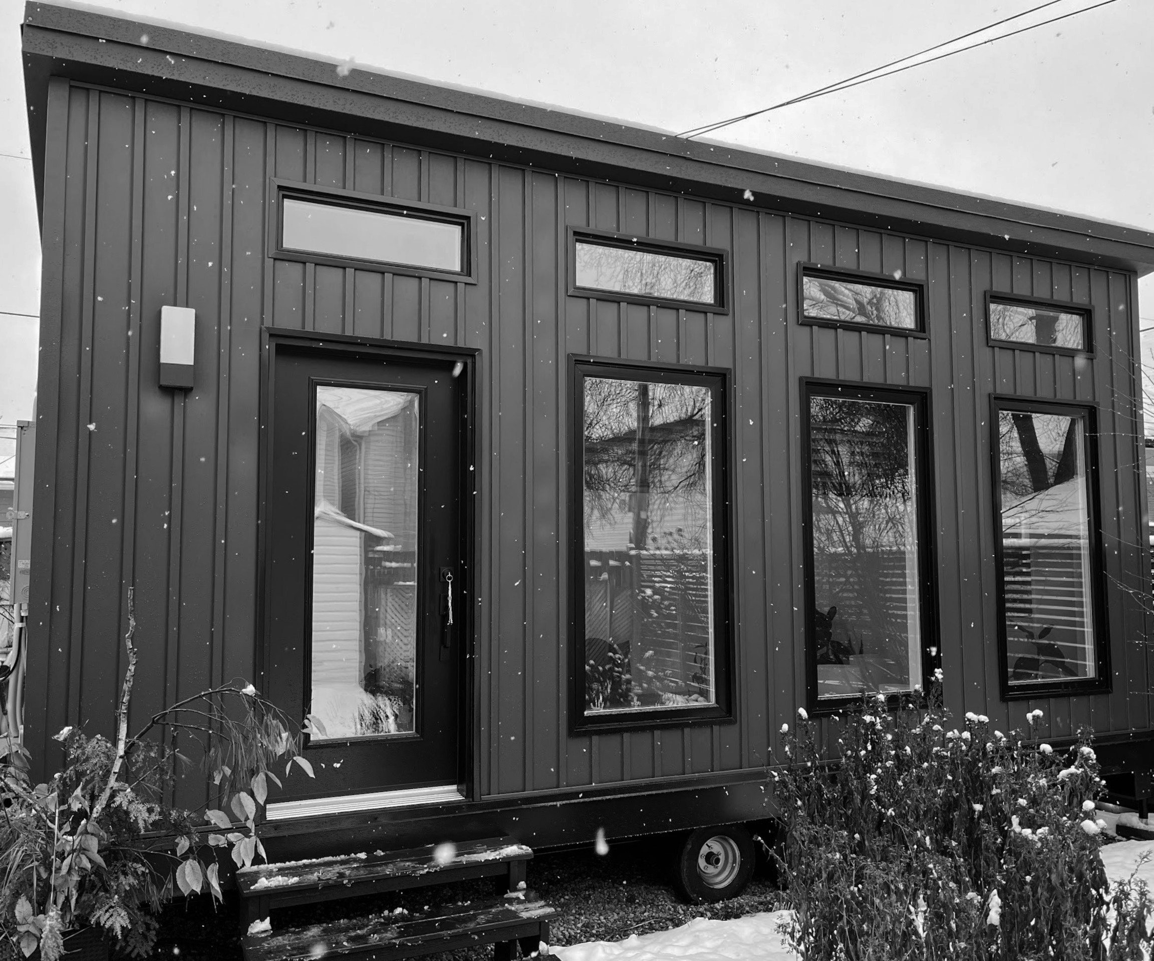 A black and white image of the exterior of an accessory dwelling unit with a front porch. 