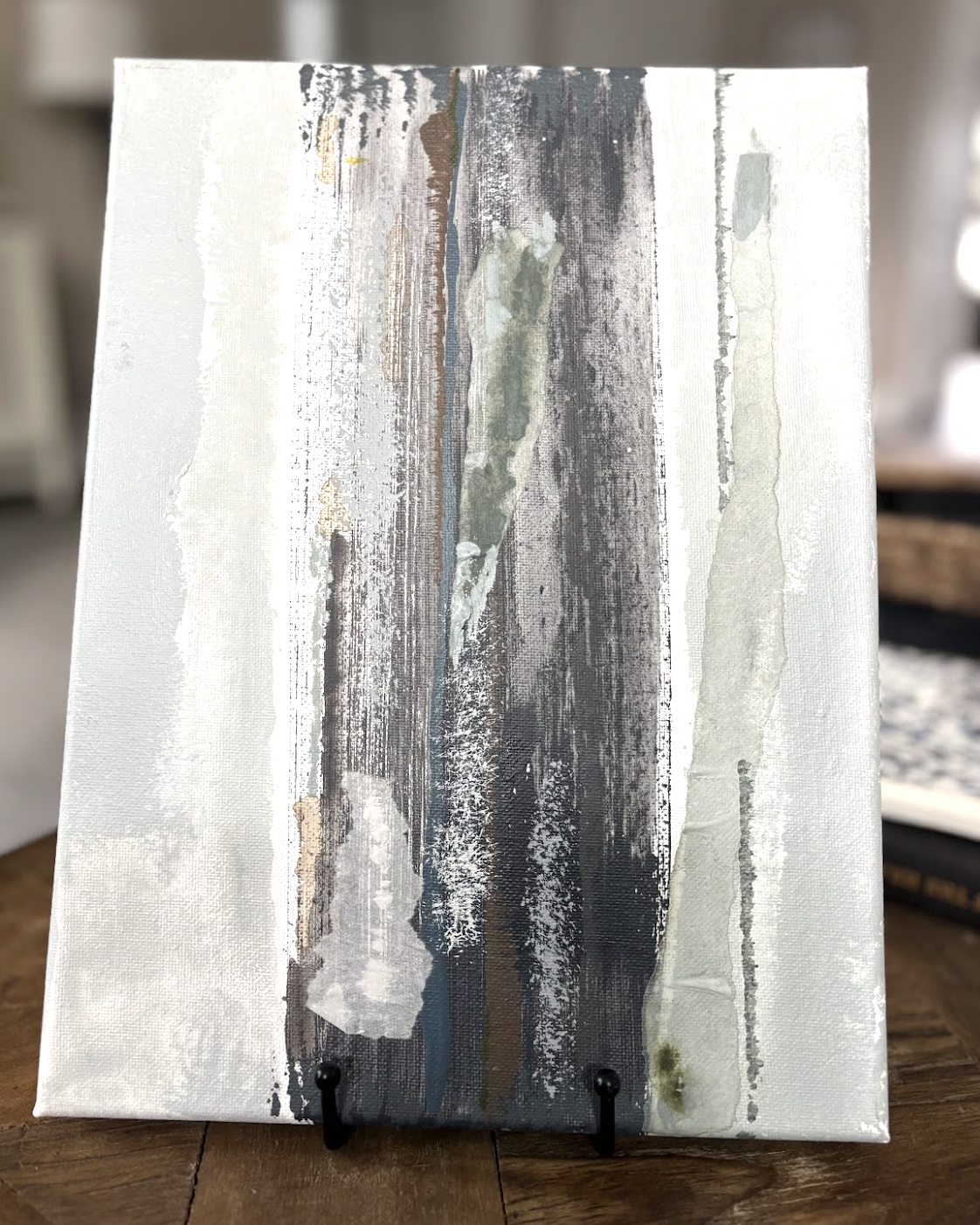 Abstract painting with vertical streaks of white, gray, black, and hints of green and beige on a small canvas.