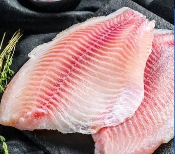 Close-up of two raw  Vertical Lake produced tilapia fish fillets on a black surface.