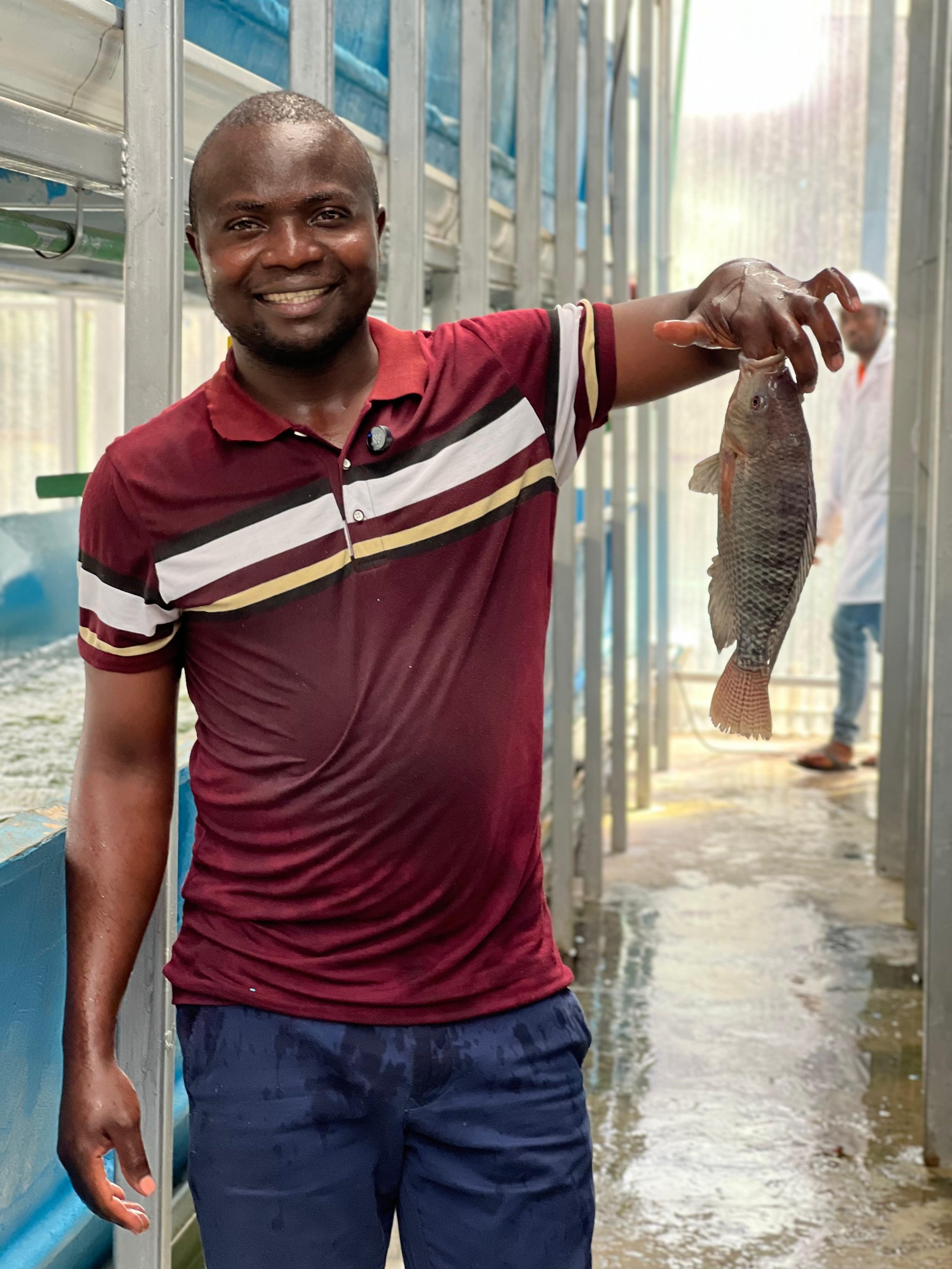 A smiling founder Jack Oyugi, holding a fish in the Vertical Lake indoor aquaculture facility.