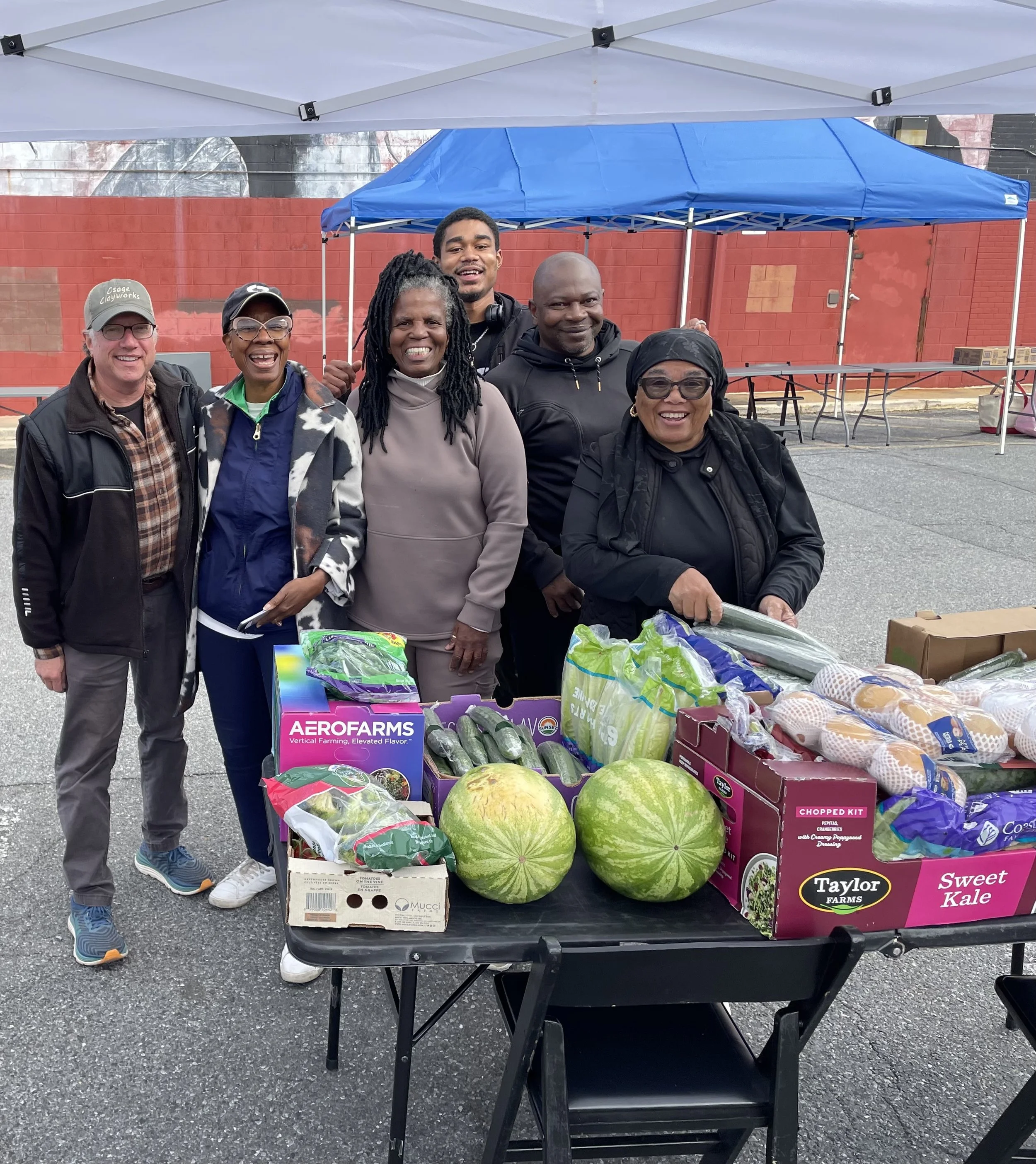 DC Food Rescue volunteer smiling with members of East of the River Family Strengthening Collaborative and a large donation of fresh produce.