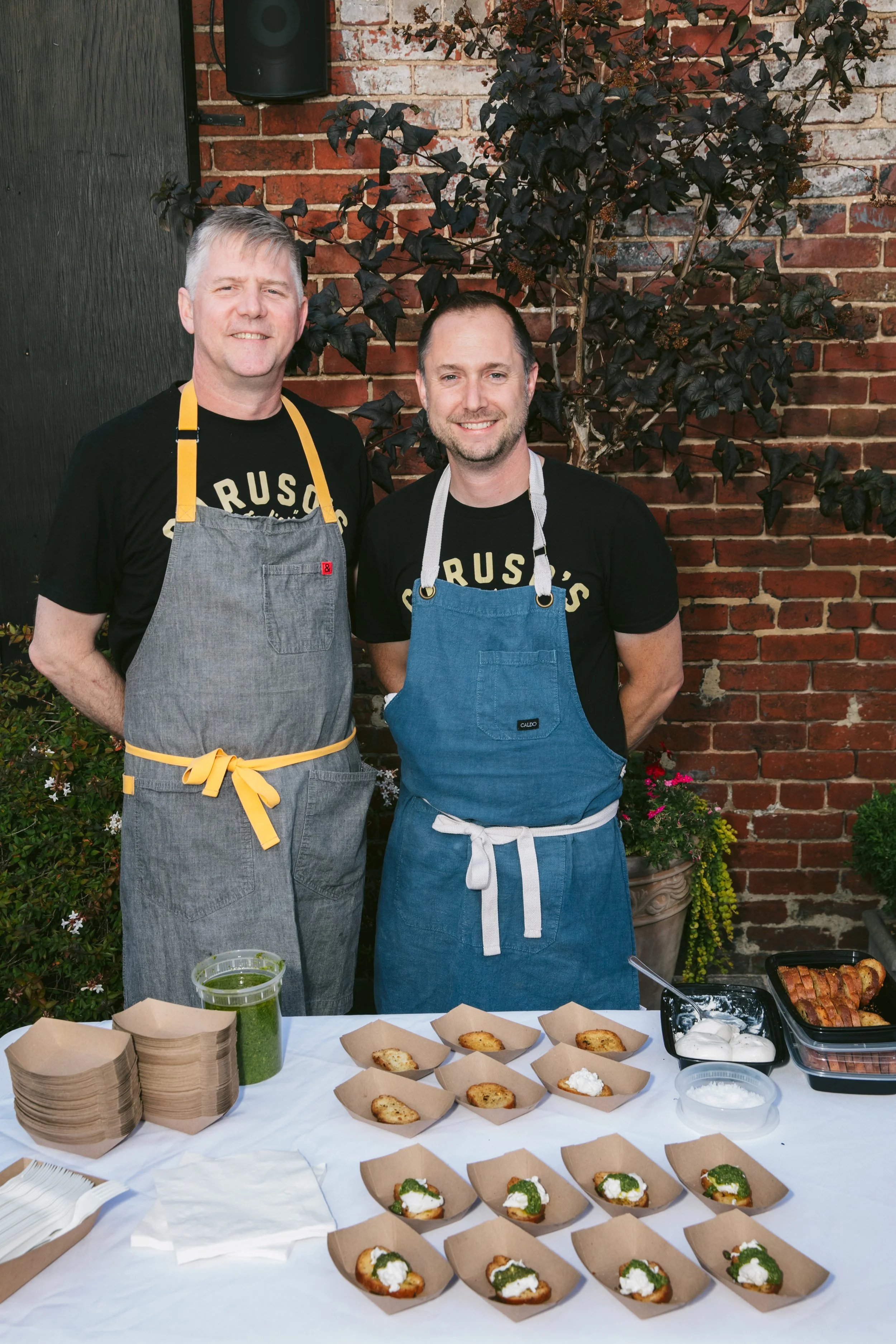 Chef Matt Adler and fellow Chef stand behind the Caruso's Grocery sample station at WE RESCUE in 2024