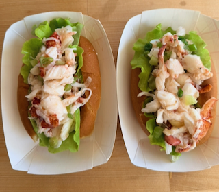 Two fresh and full lobster rolls side by side in paper trays