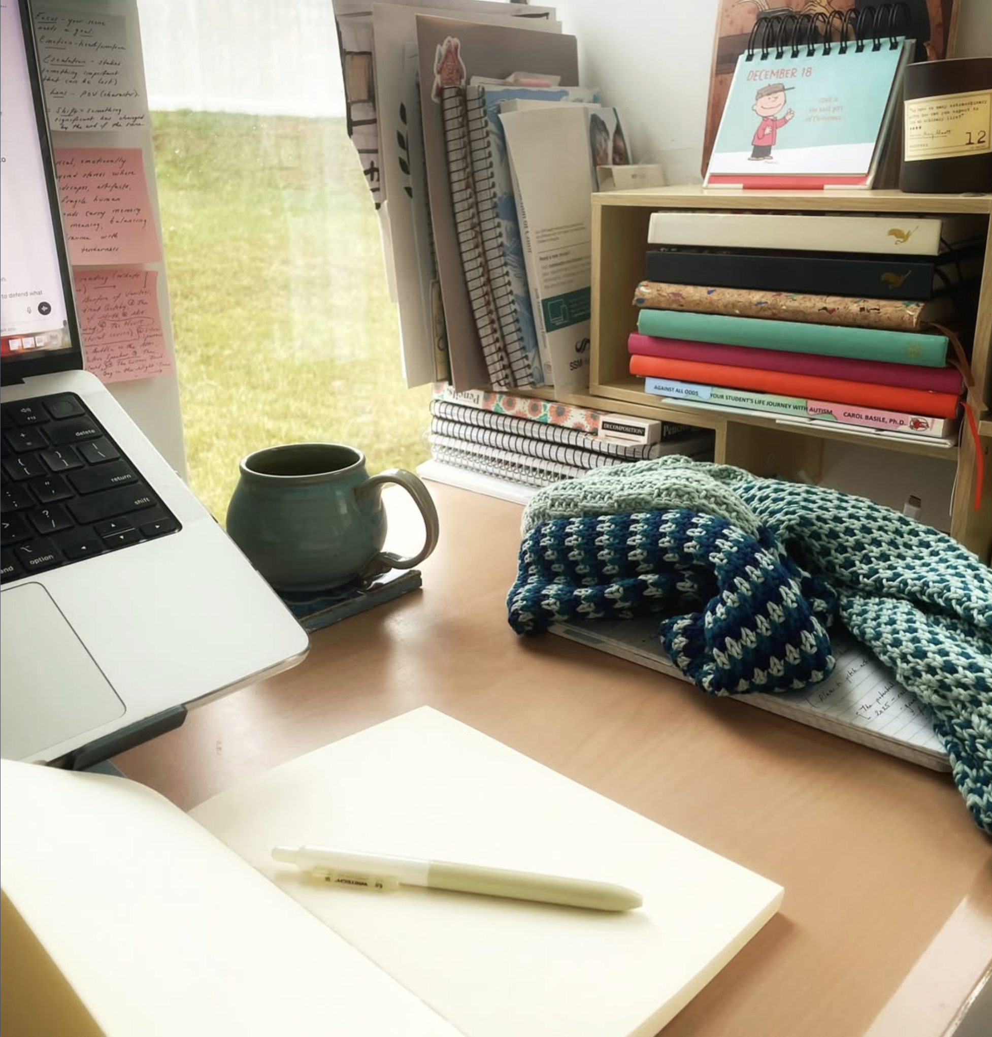 Interior studio space with open notebook, post it notes, and laptop sitting on a desk.