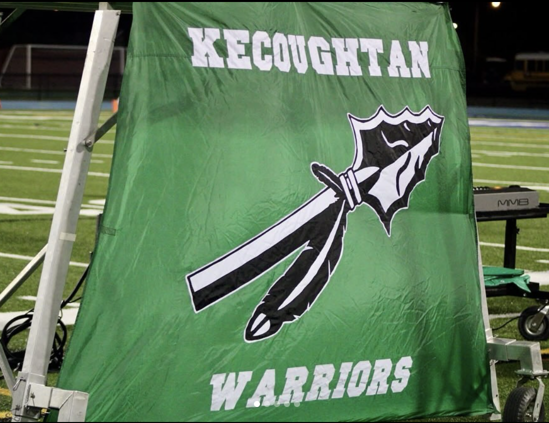 Green banner with the words 'XECOUHTAN WARRIORS' and a graphic of a dagger piercing a shield, set against a sports field background.
