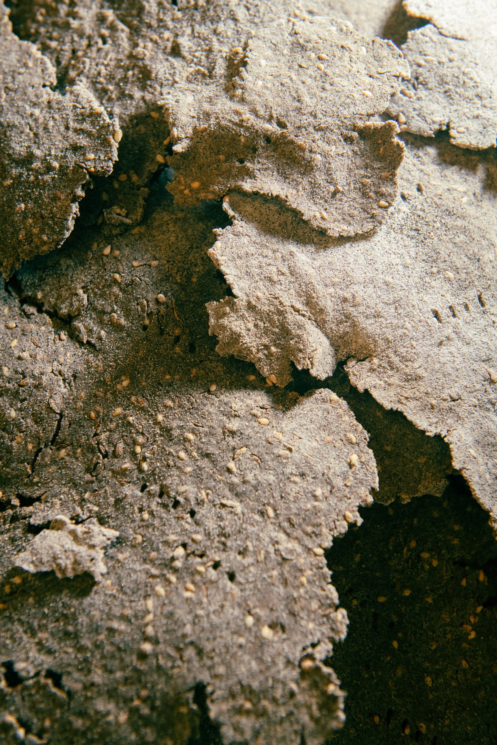 Close-up of layered, cracked, and textured earth or clay soil with small granules.