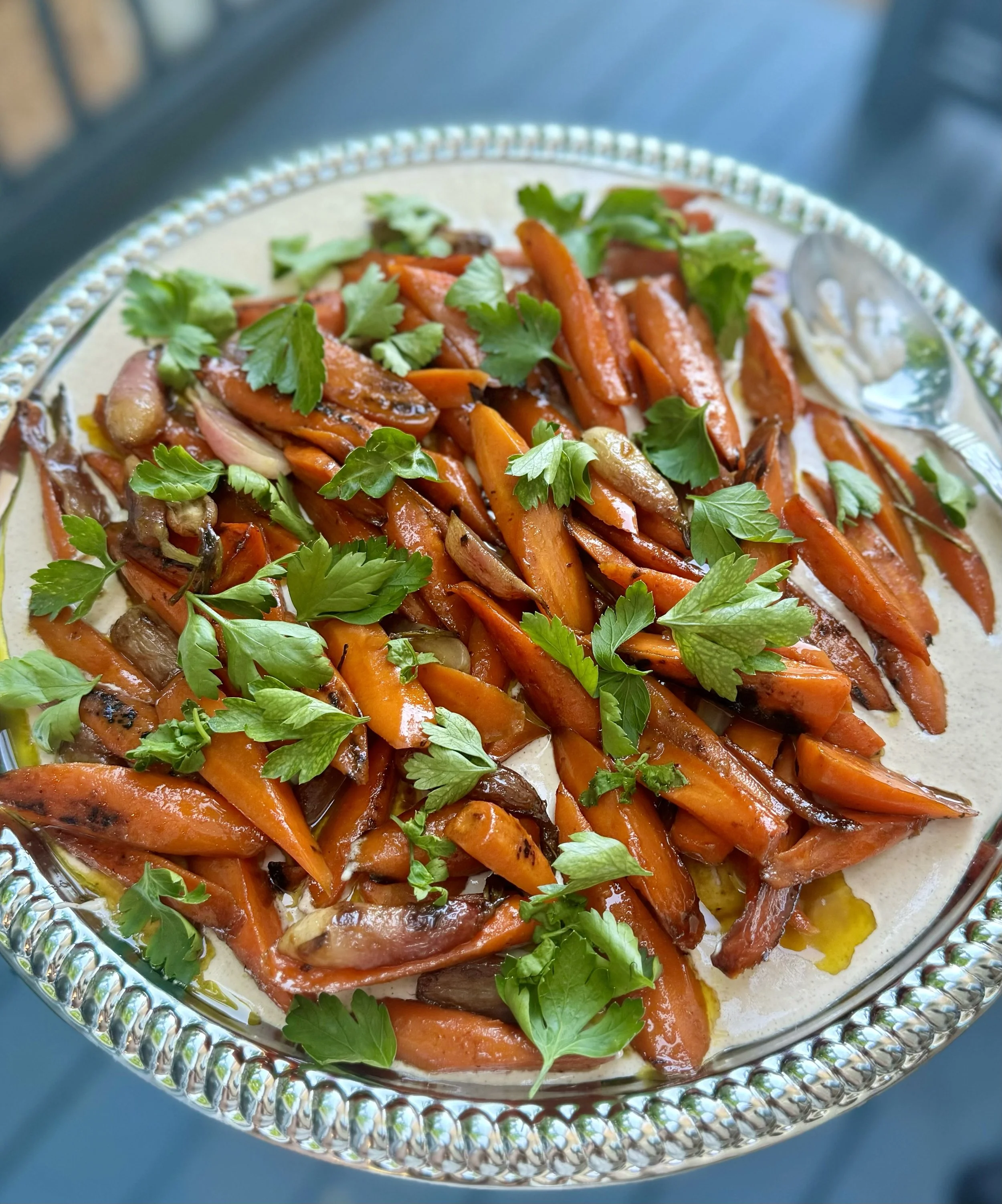 Roasted carrots garnished with fresh parsley on a silver platter.