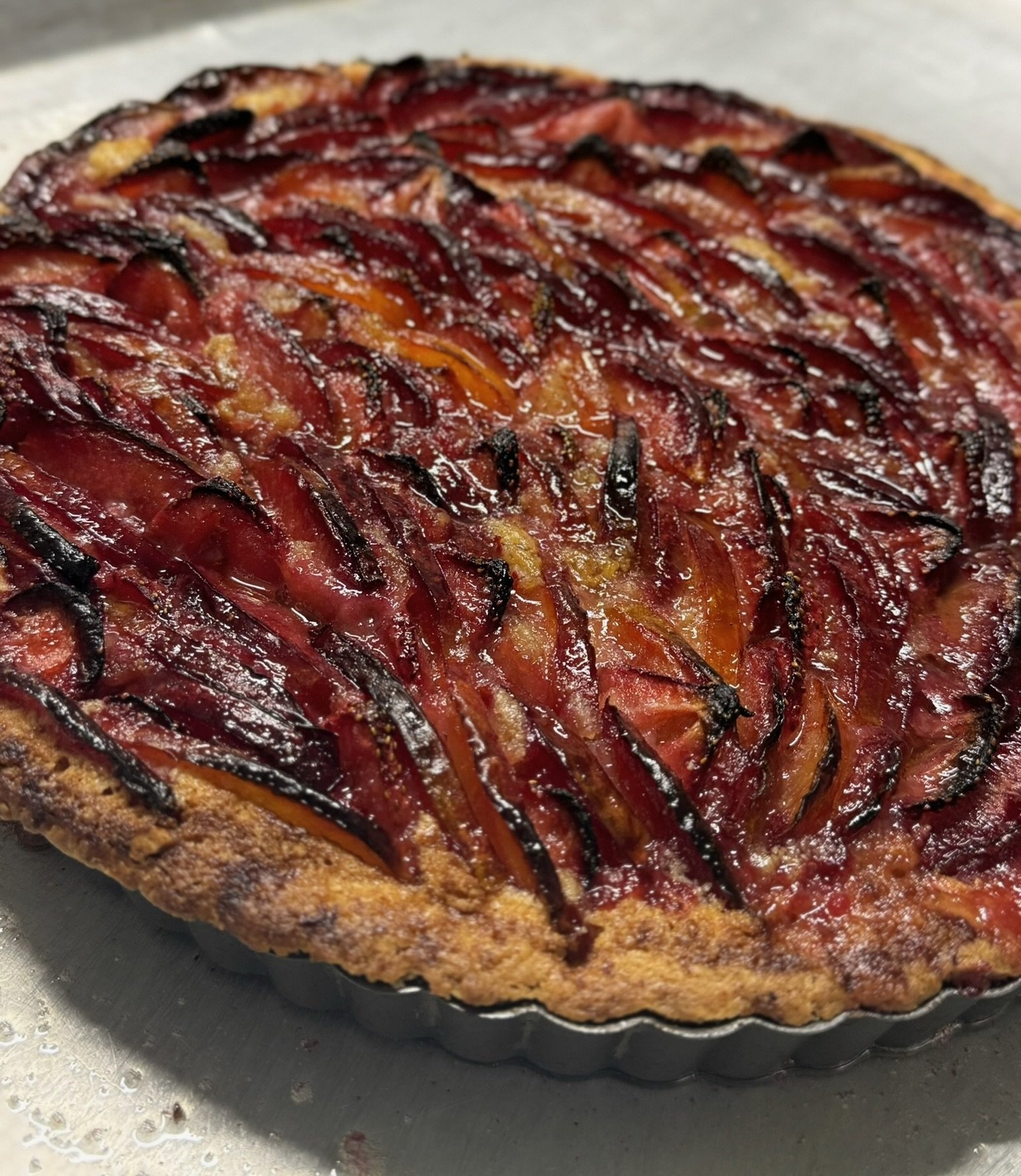Baked fruit tart with caramelized strawberries, oranges, and blackened fruit slices in a tart crust.