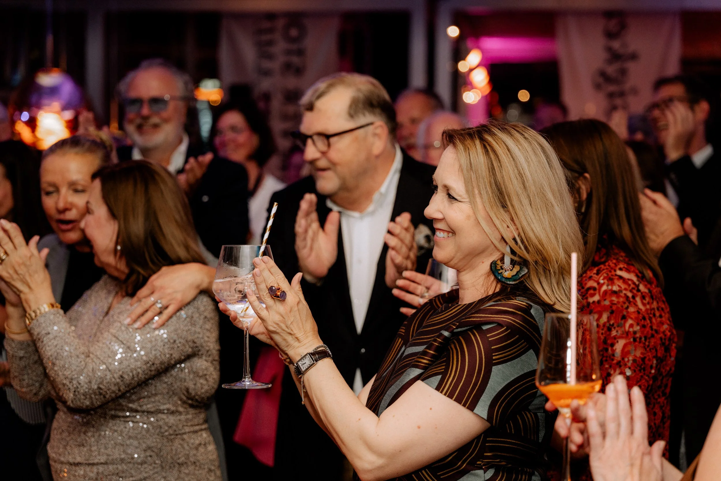 Menschen feiern bei einer Party, lachen und stoßen mit Getränken an.