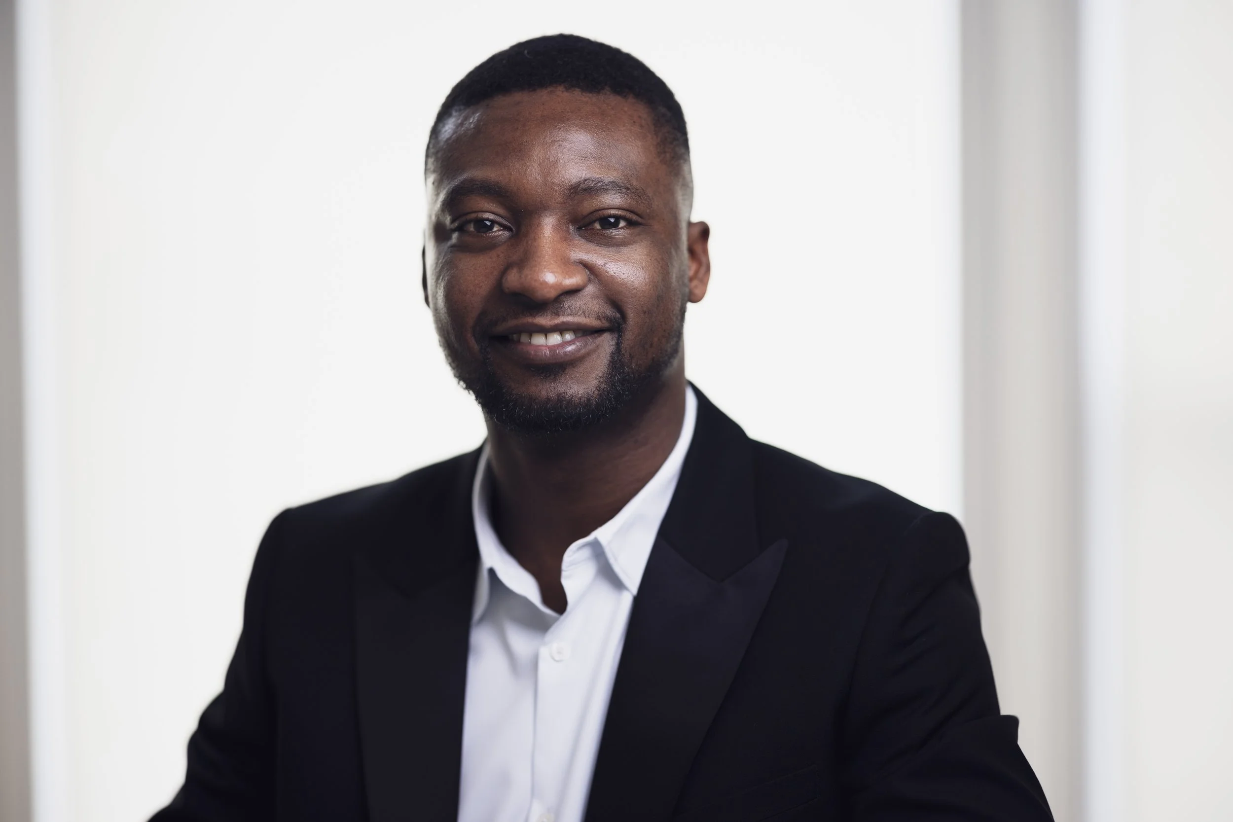A smiling African American man in a black suit and white shirt, looking at the camera.