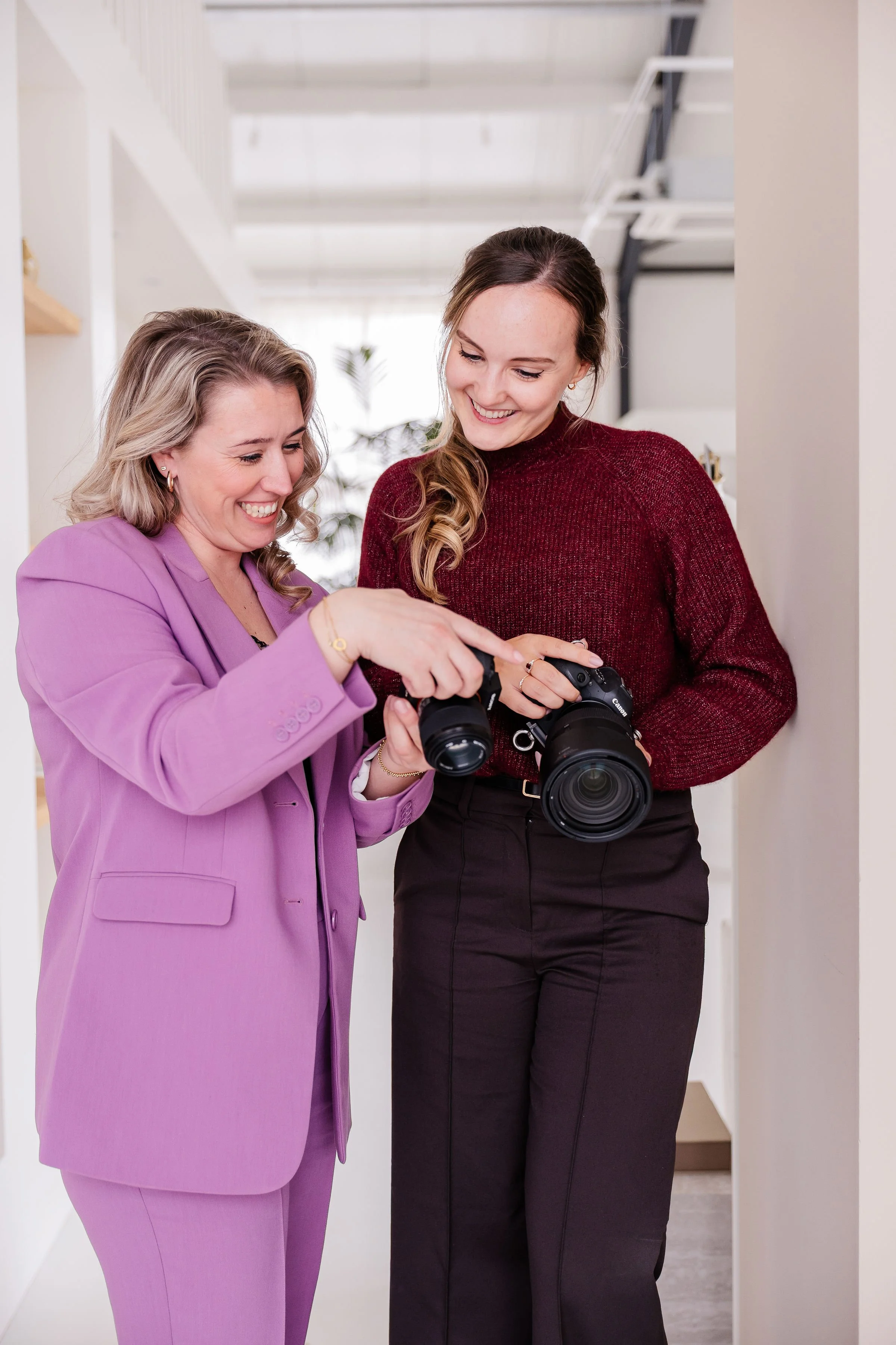 Twee vrouwen kijken samen naar een camera. Ze lachen en lijken te genieten van het moment.