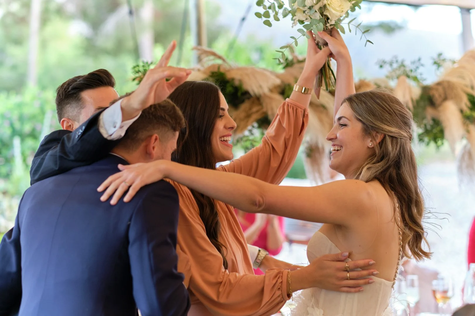 Grupo de personas felices en una celebración, con una mujer en vestido de novia sonriendo y rodeada de amigos en una fiesta.