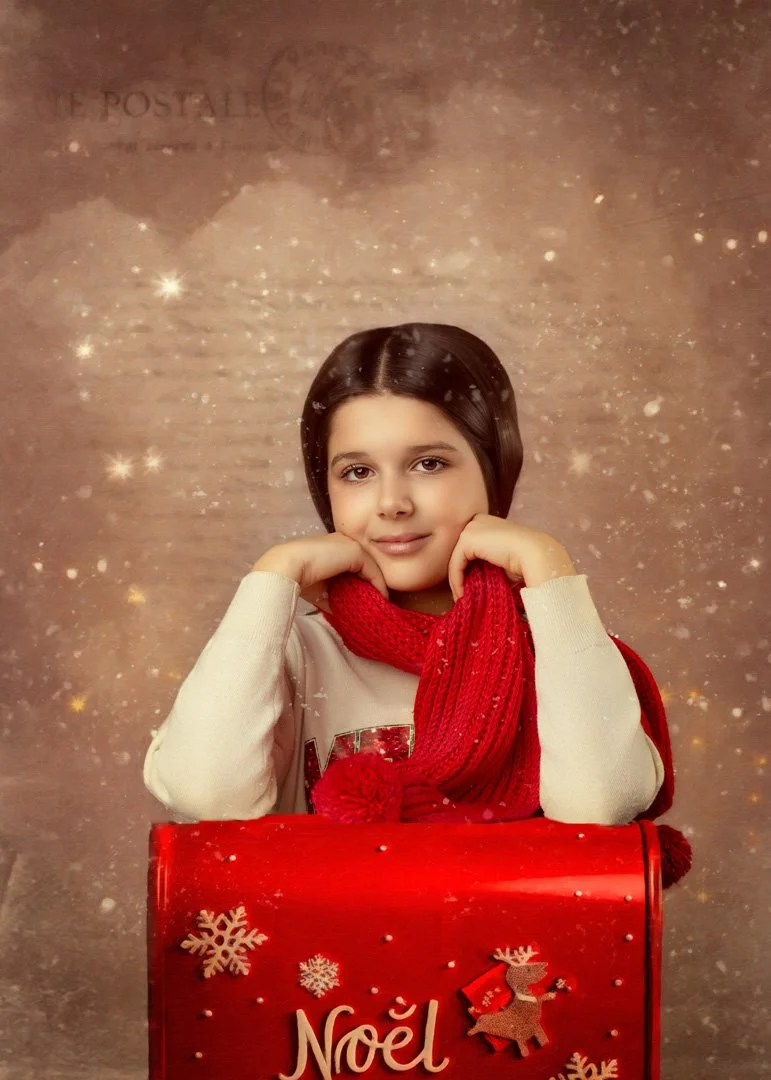 Joven niña posando con una bufanda roja celebrando Navidad, en un fondo con efecto de nieve y partículas brillantes, sosteniendo una caja de regalo roja con decoraciones navideñas.