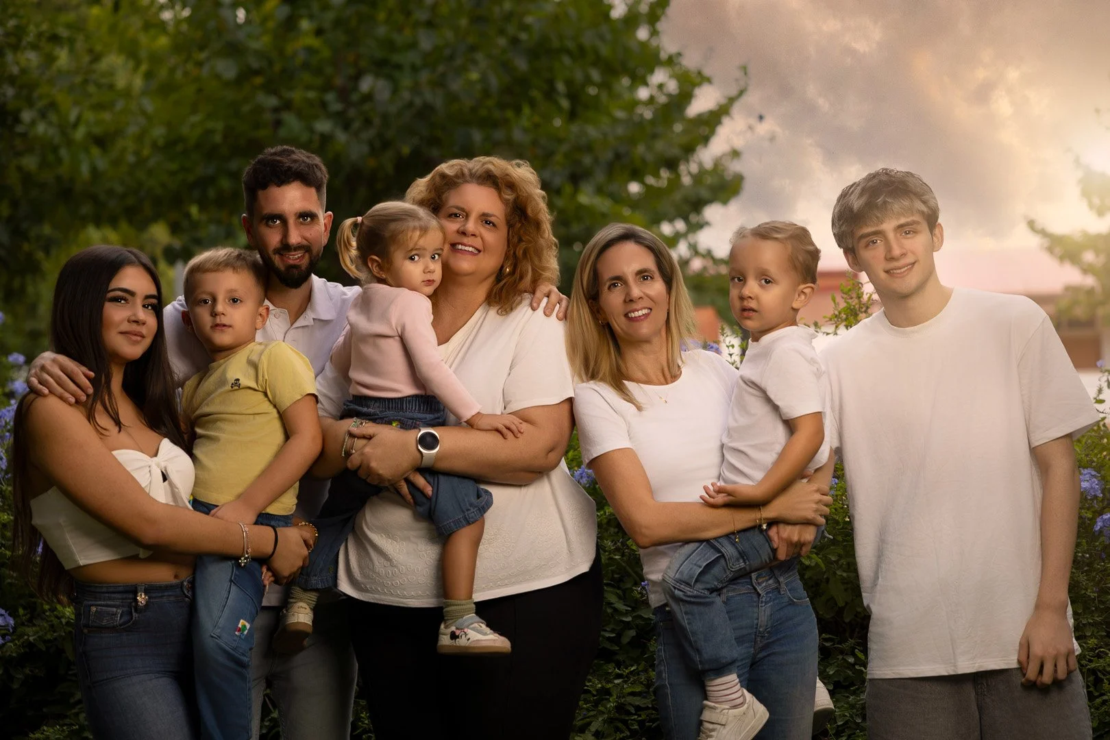 Grupo de varias personas en un entorno natural al atardecer, incluyendo niños, adultos y adultos mayores, sonriendo y posando para la foto.
