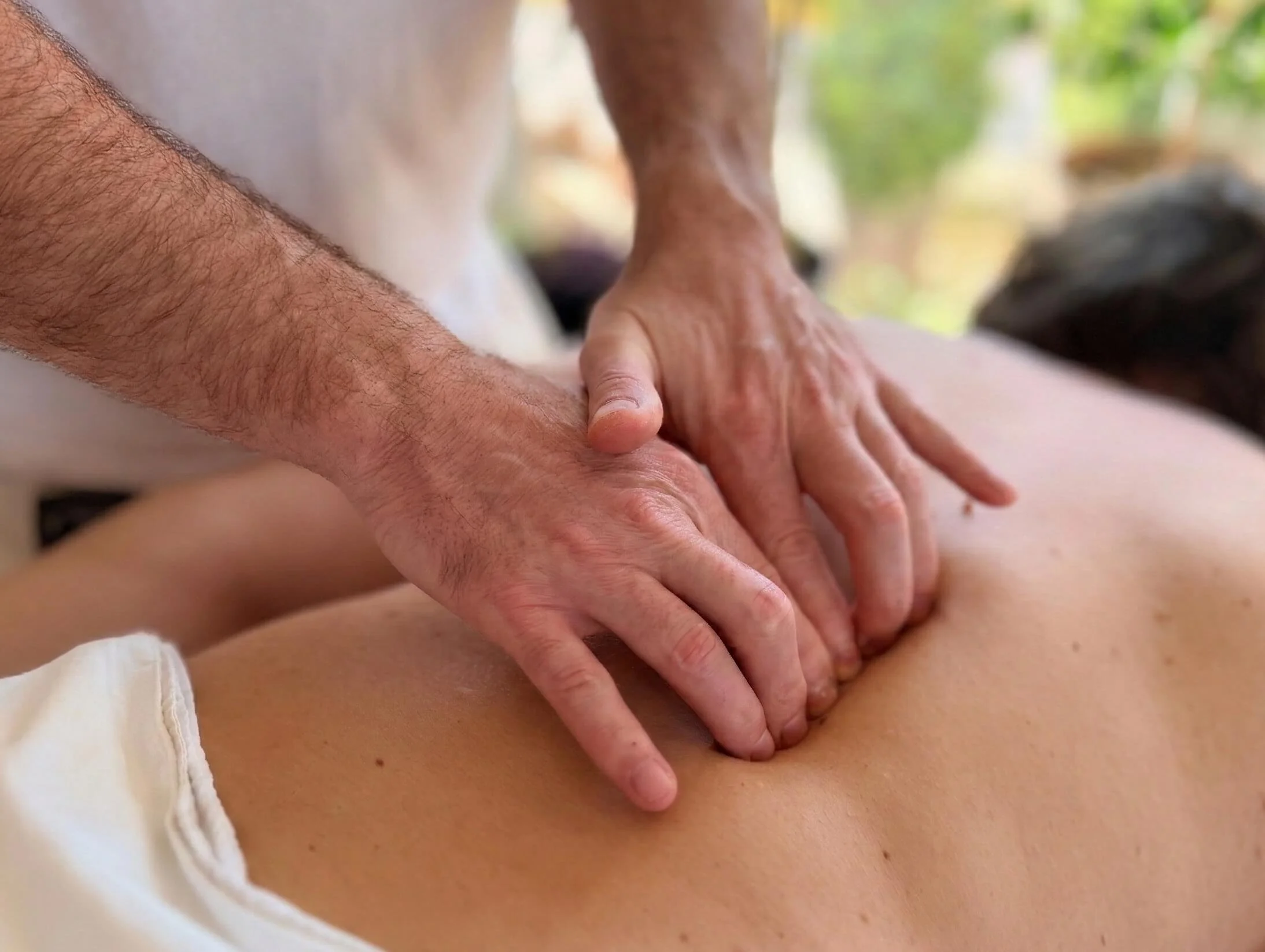 Maser koristi ruke kako bi pružio masažu na leđima osobe na otvorenom.