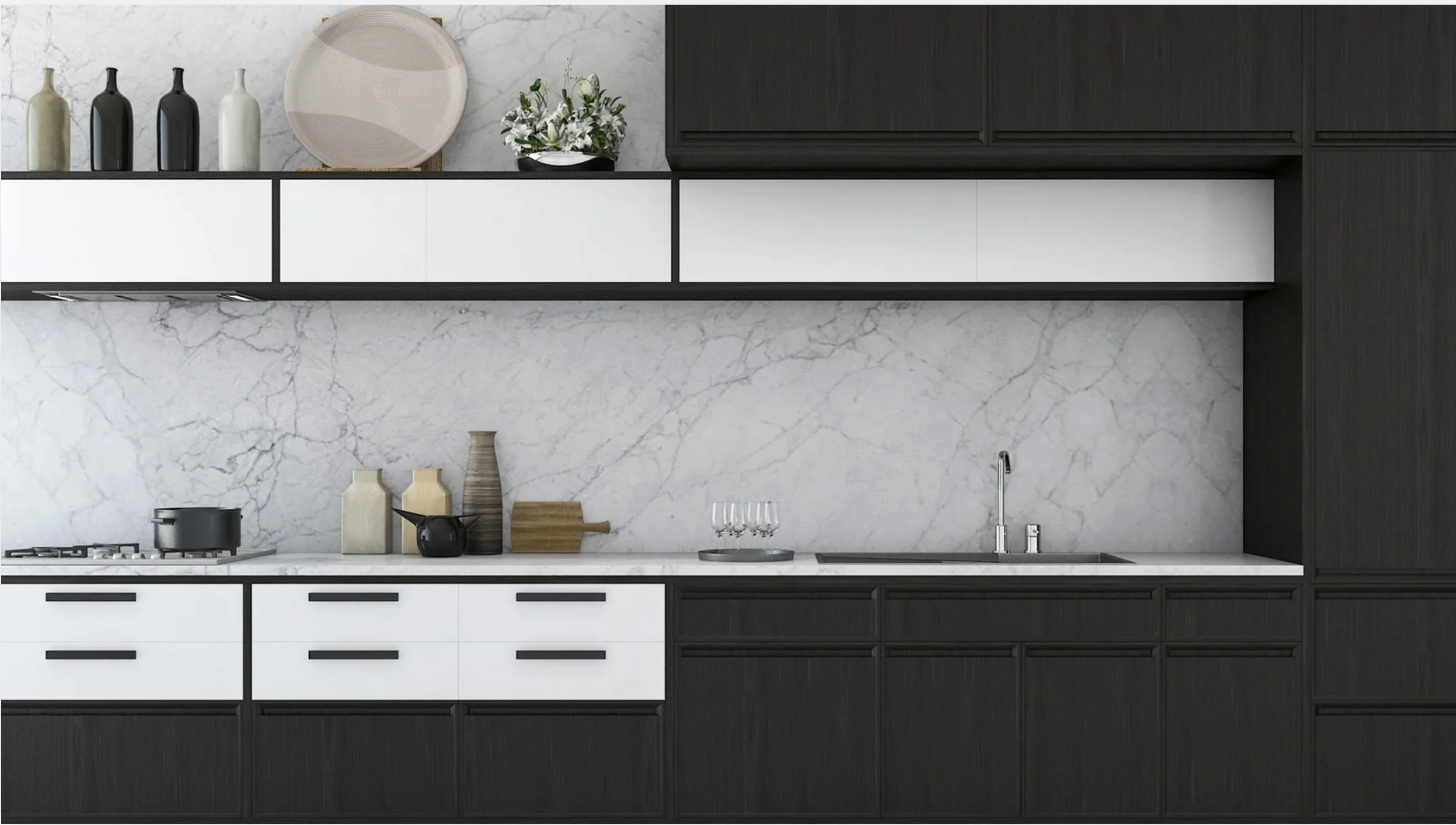 Modern kitchen with black and white cabinetry, marble backsplash and countertop, a sink with chrome faucet, decorative vases, a plant, white plates, a pot on the stove, and wine glasses.