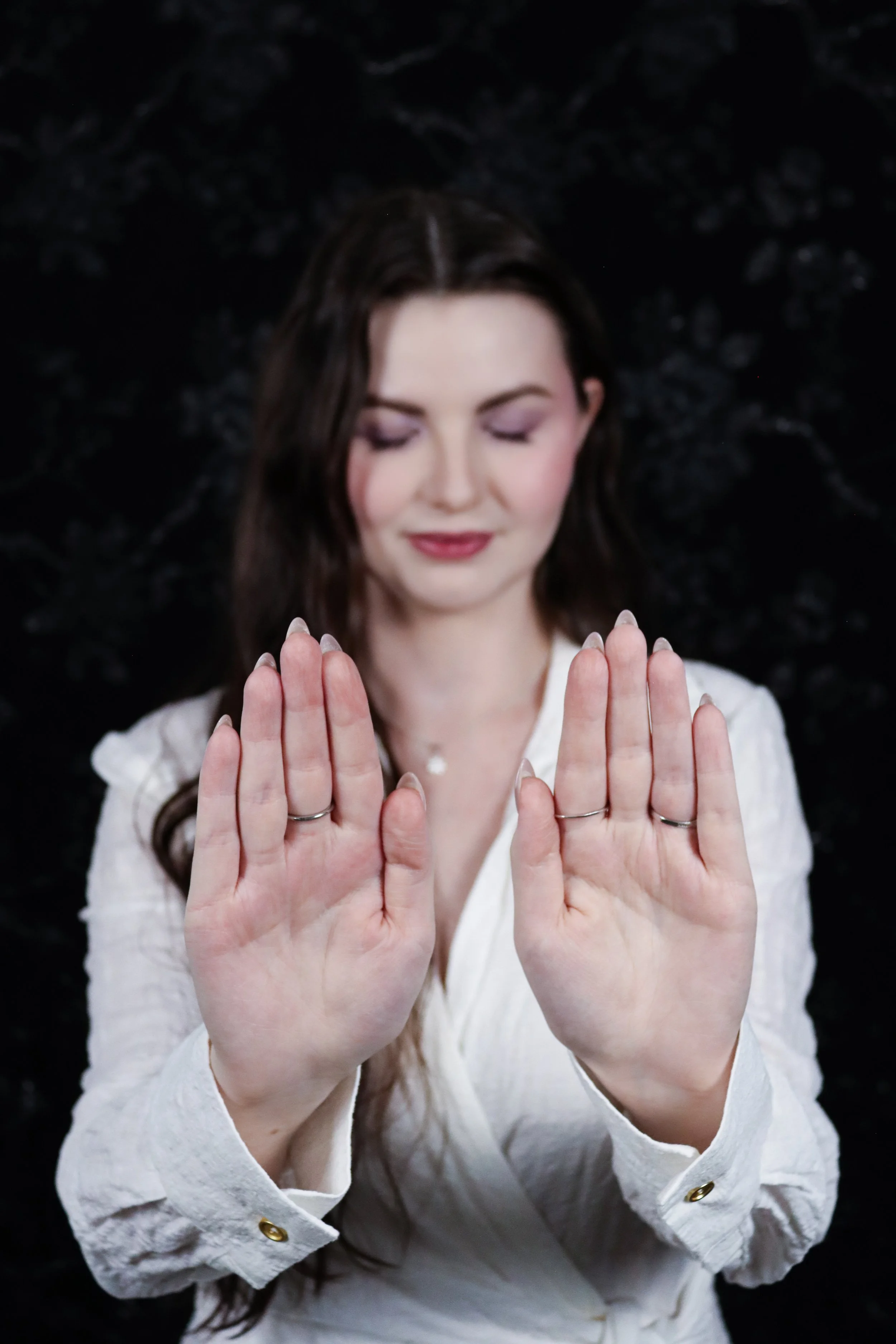 Woman in white shirt holding hands up and giving Reiki.
