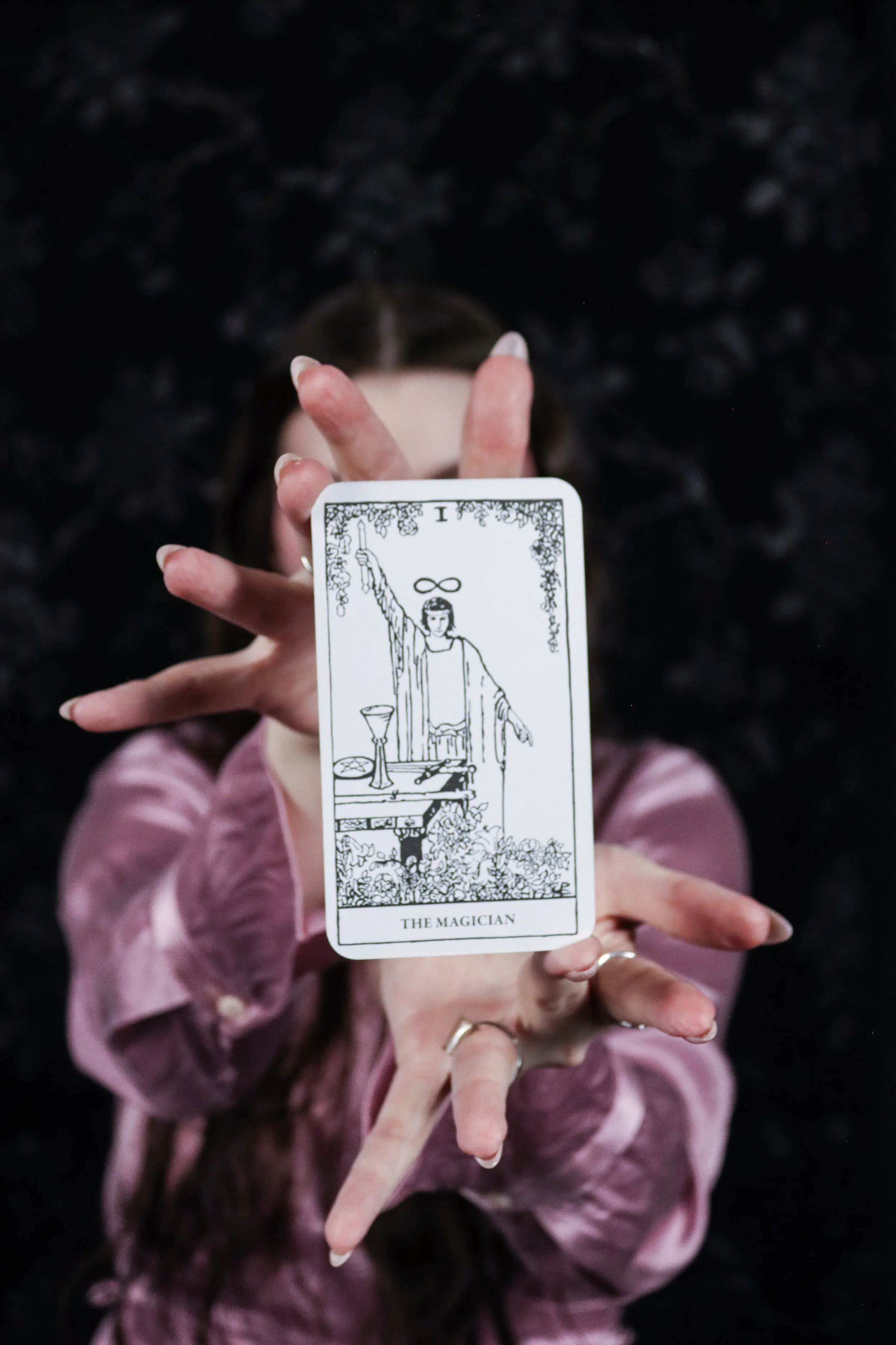 Woman holding The Magician Tarot card out in front of her.