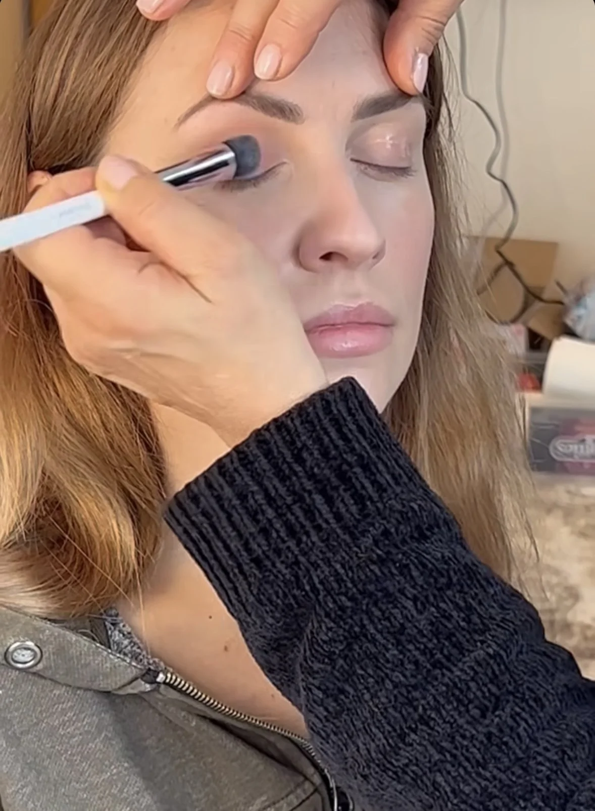 Professional makeup artist applying eye makeup to client