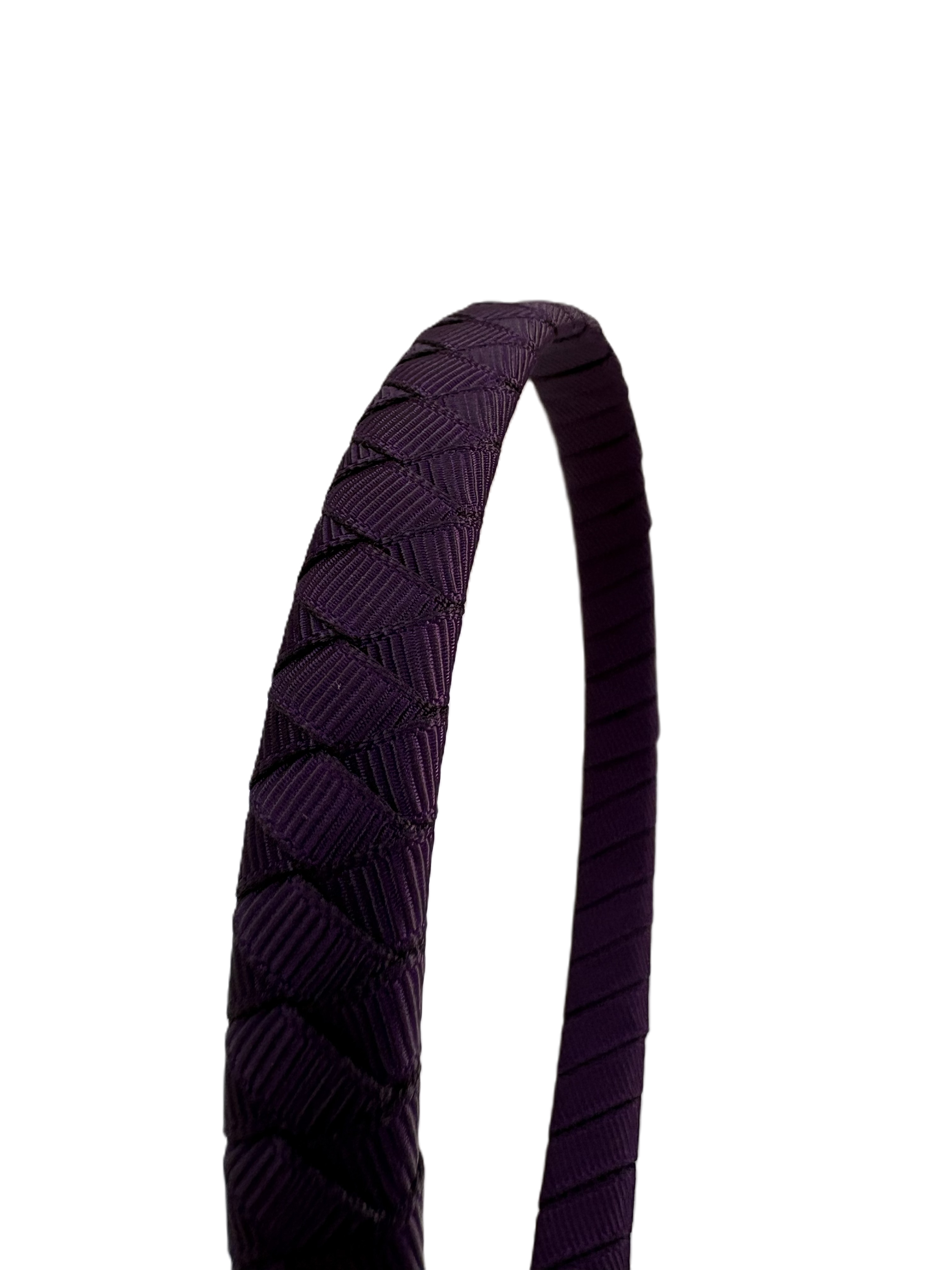Close-up of a dark purple headband with textured pattern on a white background.