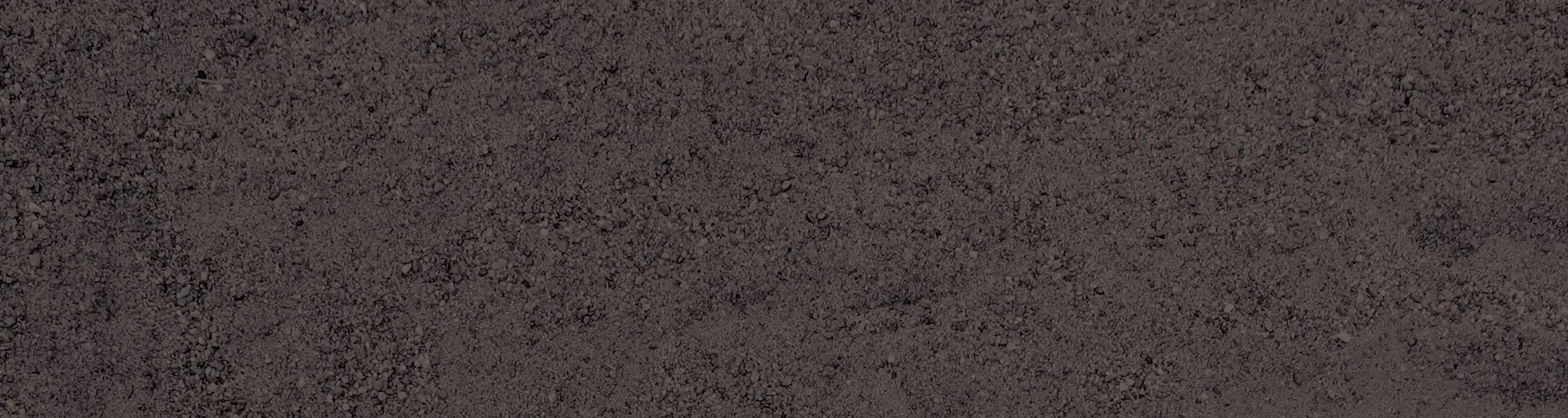 Close-up of asphalt pavement surface with small stones and granular texture.