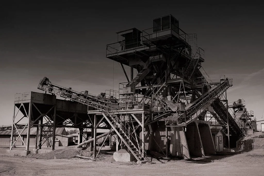 Black and white industrial mining structure with stairs and conveyer belts.