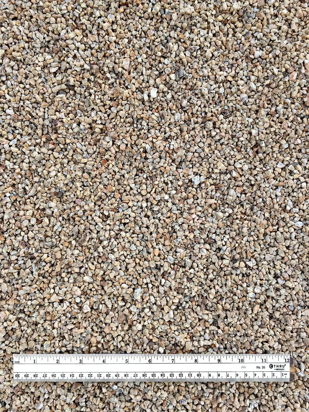 Close-up of small, multicolored gravel stones with a measuring ruler at the bottom for scale.