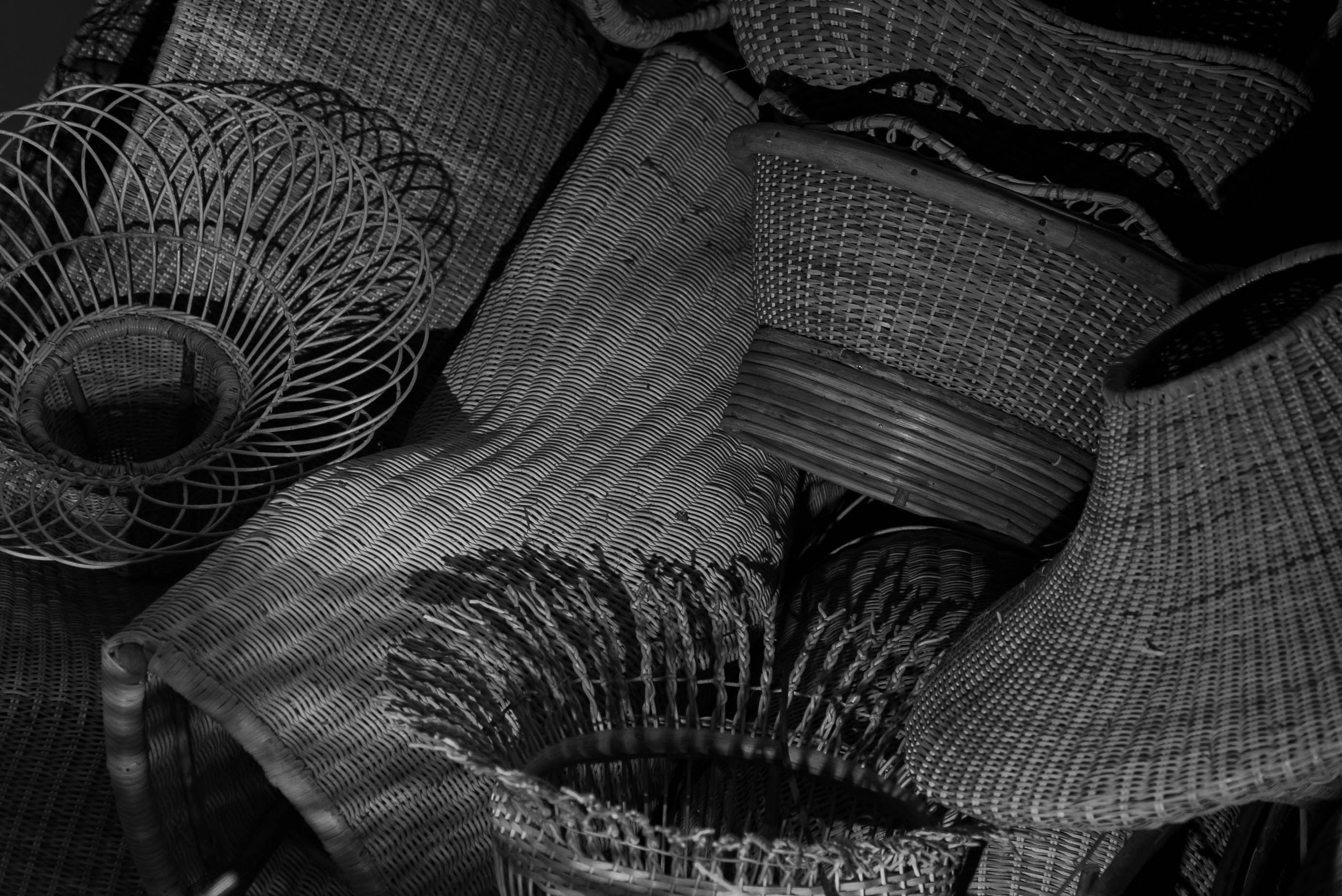 A collection of woven wicker baskets and curved furniture pieces arranged in a pile.