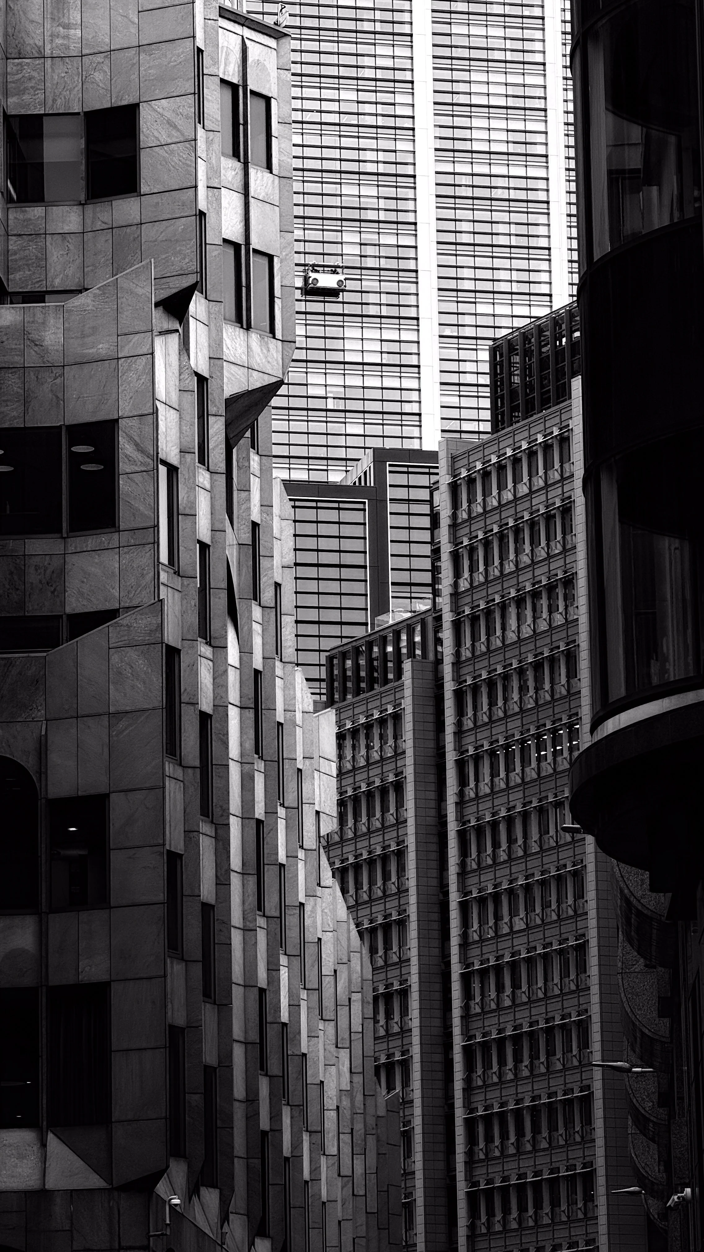 Black and white photo of several modern high-rise buildings with various window patterns and architectural styles in an urban cityscape.