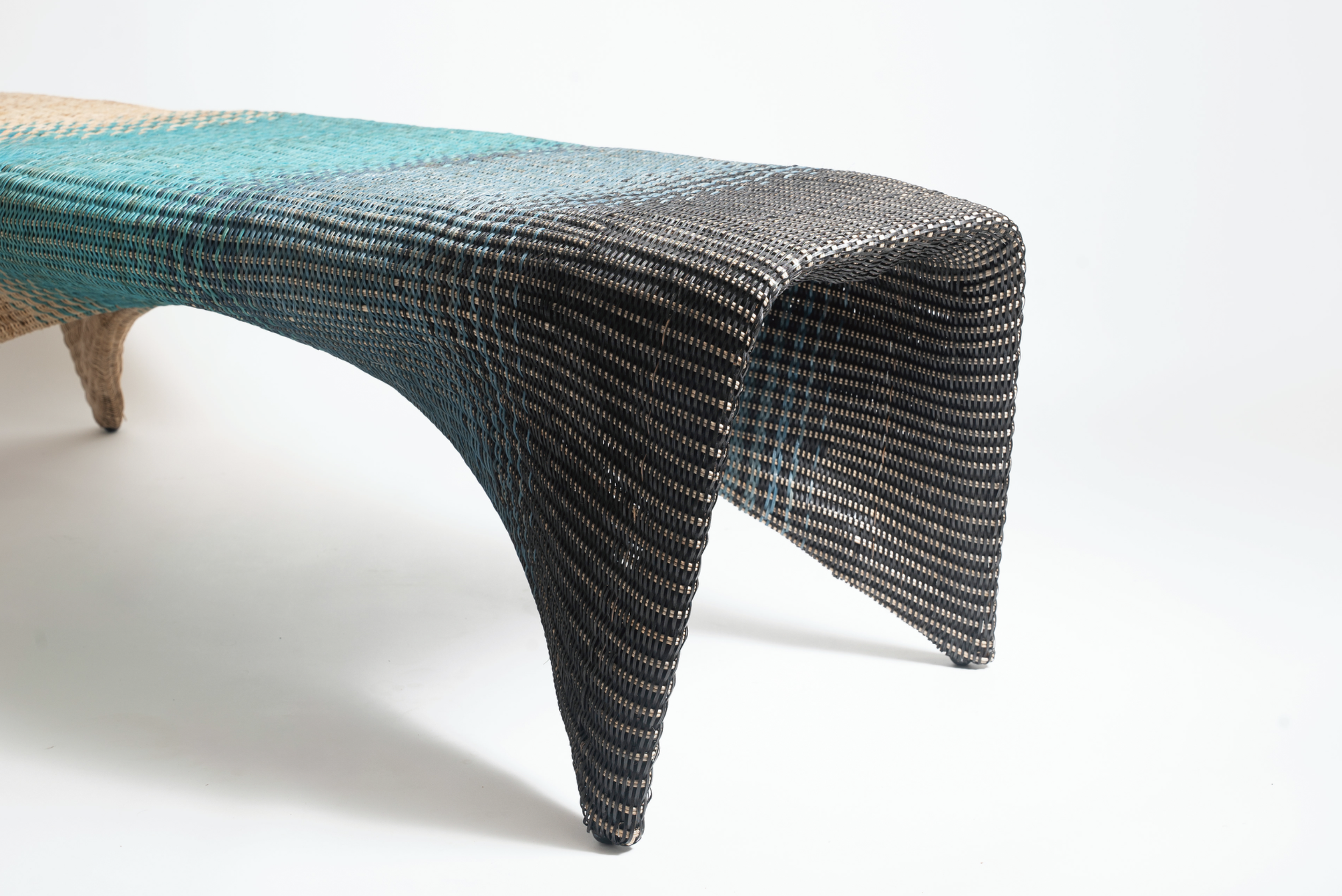 Colorful woven bench with curved legs against a white background.