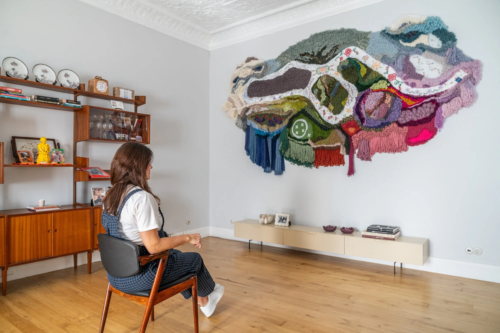 The artist contemplating 'A Ilha', a completed wall-art piece featuring organic wool and Madeira Embroidery.