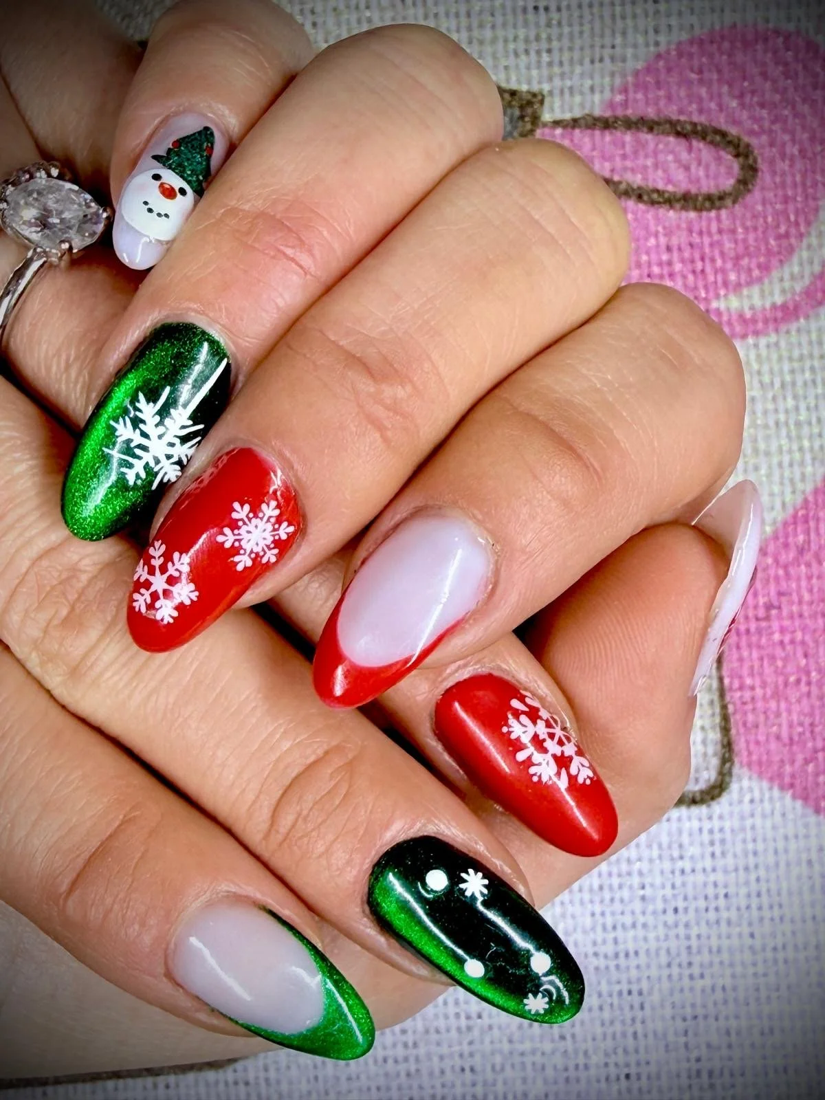 Festive Christmas nail art with snowflakes, a snowman, and holiday themes in red, green, and white colors.