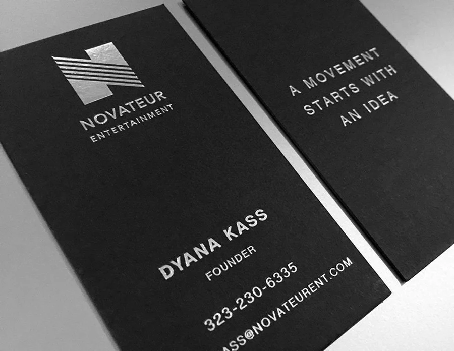 Black business card featuring the Novateur Entertainment logo, founder Dyana Kass's name, contact number, and email, beside an additional card with the quote "A movement starts with an idea."