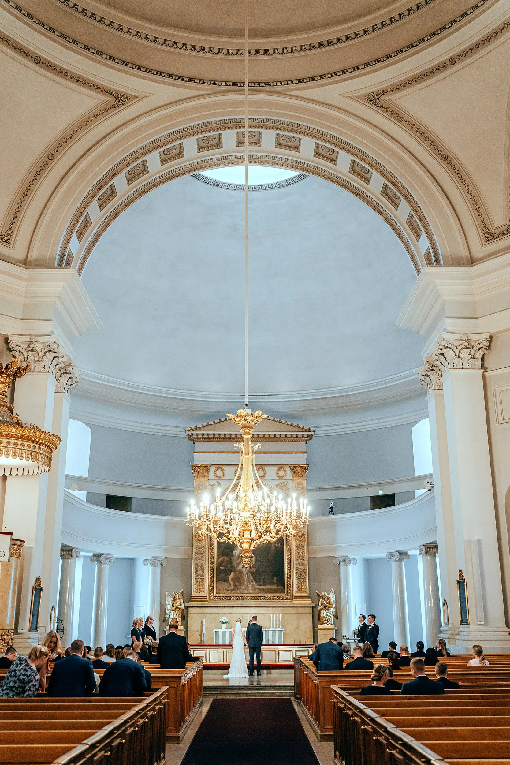 Majesteettinen kuva hääparin vihkimisestä Helsingin tuomiokirkon korkeiden holvikaarien alla. Hääkuvaus Helsinki – hyvän mielen hääkuvaaja Sami Turunen.