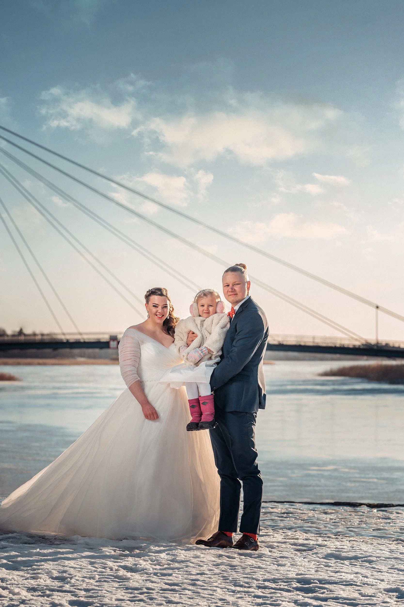 Hääpari hymyilee talvimaisemissa kuohuvan Vanhankaupunginkosken rannalla. Hääkuvaus Helsinki - Hyvän mielen hääkuvaaja Sami Turunen.