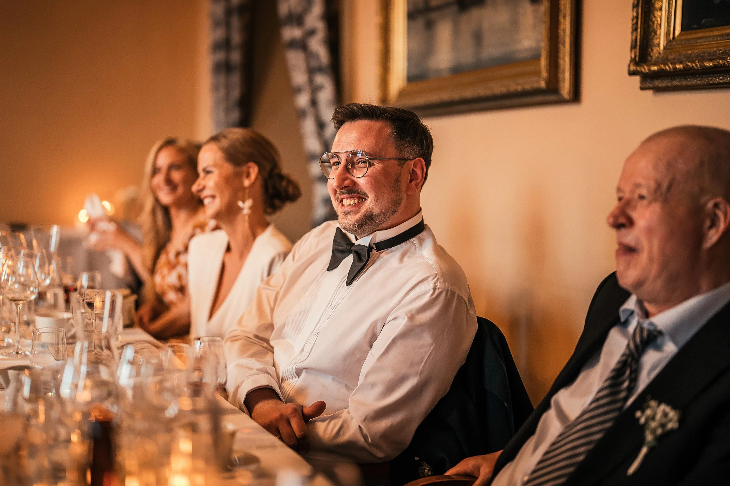 Hääparia naurattaa bestmanin puhe juhlapaikalla Restaurant Havenissa. Hääkuvaus Helsinki - Hyvän mielen hääkuvaaja Sami Turunen.