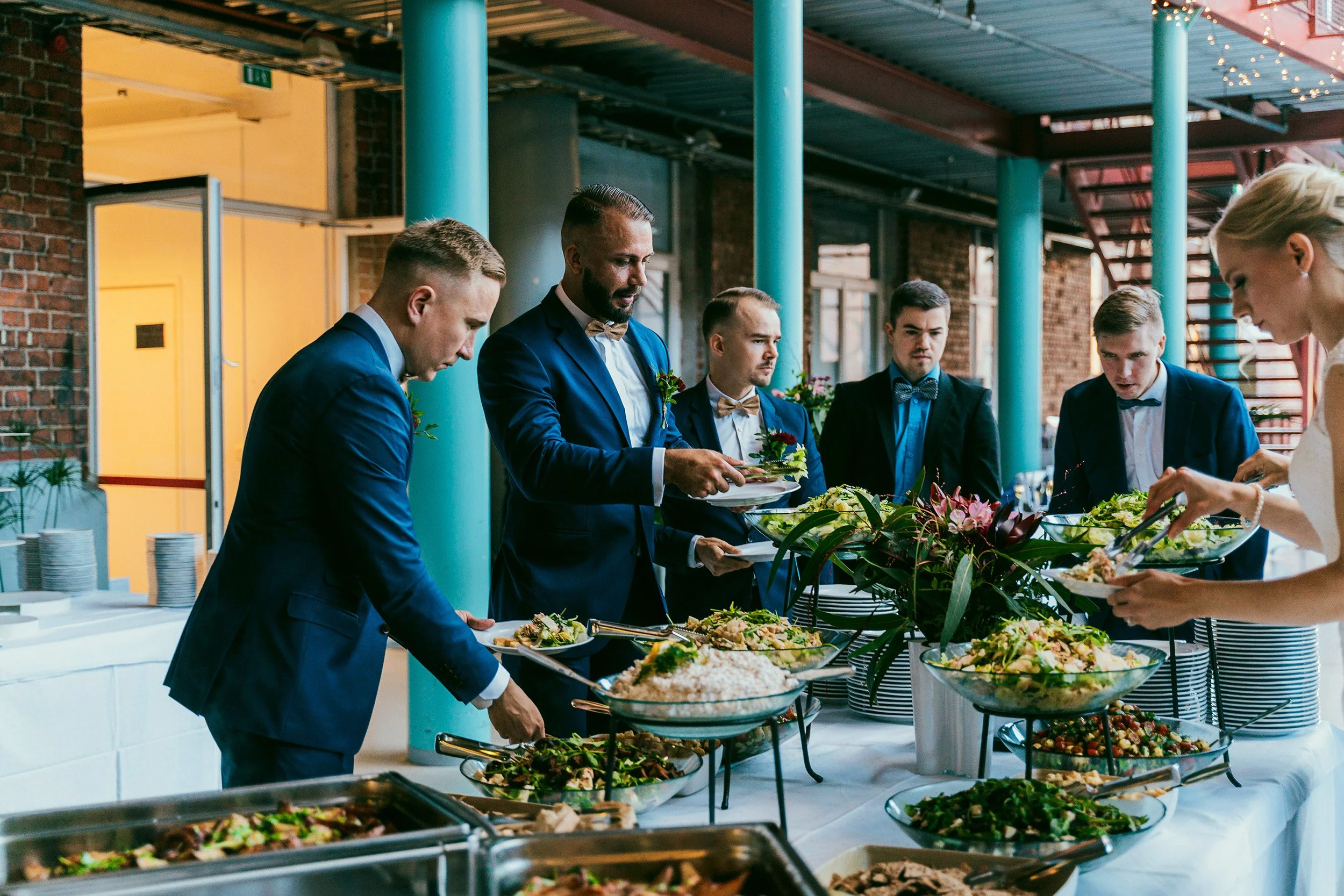 Bestmanit ja kaasot hääbuffetin äärellä Klondyke-talossa. Hääkuvaus Kerava – hyvän mielen hääkuvaaja Sami Turunen.