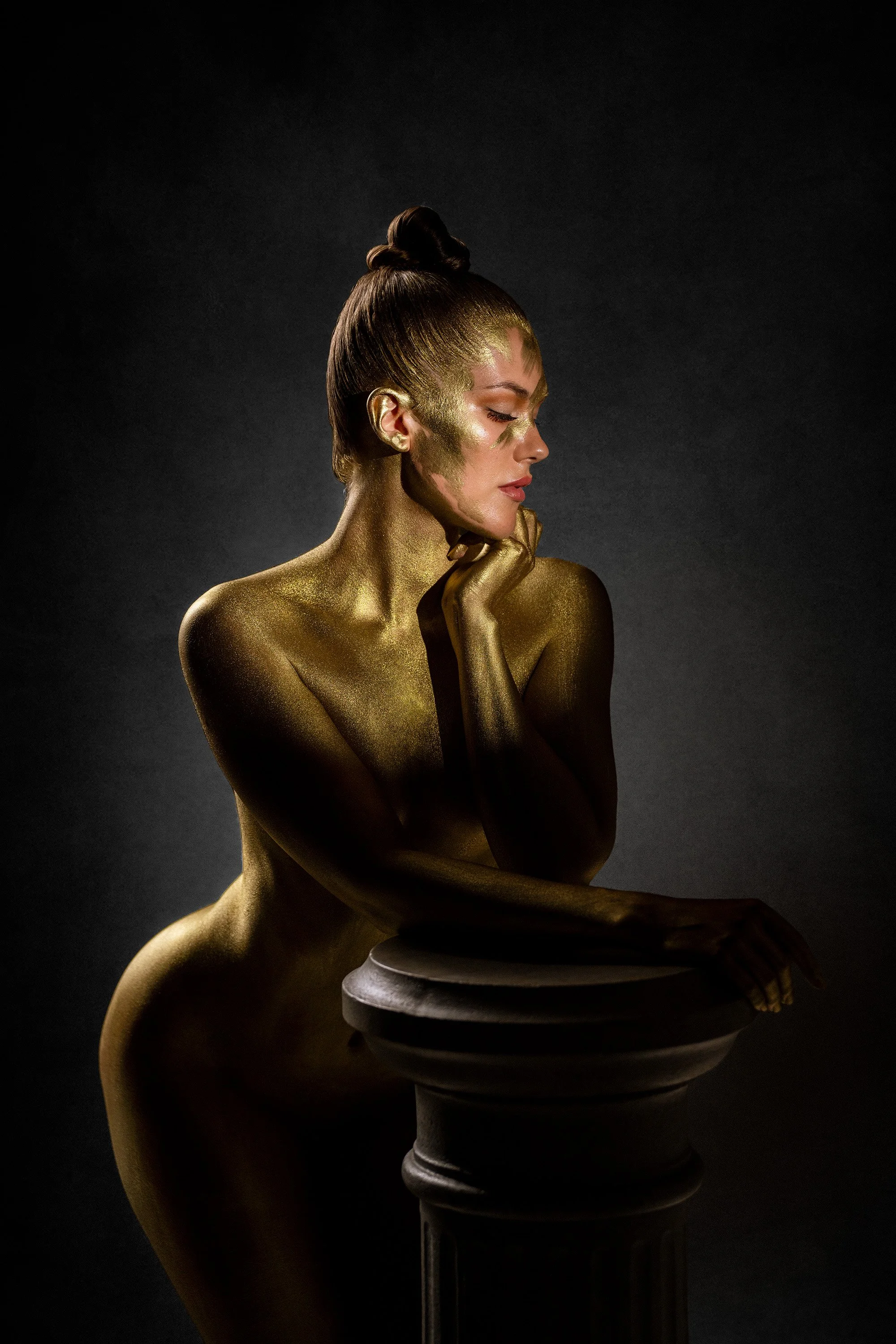 Fanny Mustalahti nojaa antiikkiseen korokkeeseen kokovartalo-bodypainting-kuvassa, jossa vartalo on maalattu kultaiseksi. Bodypainting-taiteilija: Riina Laine. Luova muotokuvaus Helsinki – hyvän mielen valokuvaaja Sami Turunen.