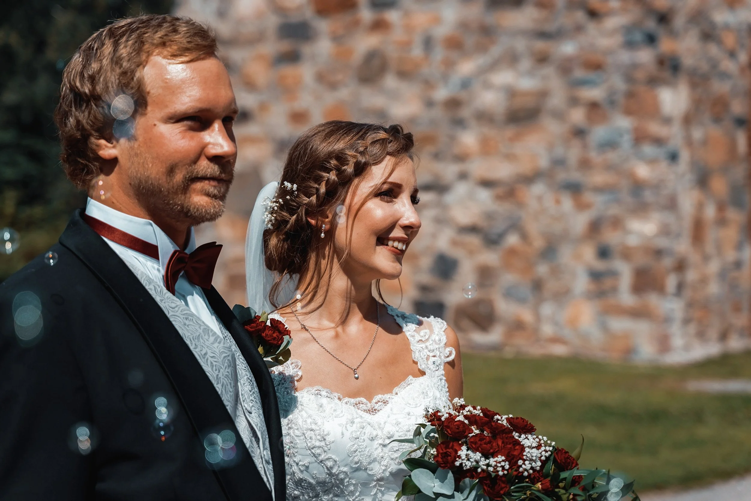 Hääpari saippuakuplasateessa vihkimisen jälkeen Pyhän Laurin kirkon pihalla. Hääkuvaus Vantaa – hyvän mielen valokuvaaja Sami Turunen.