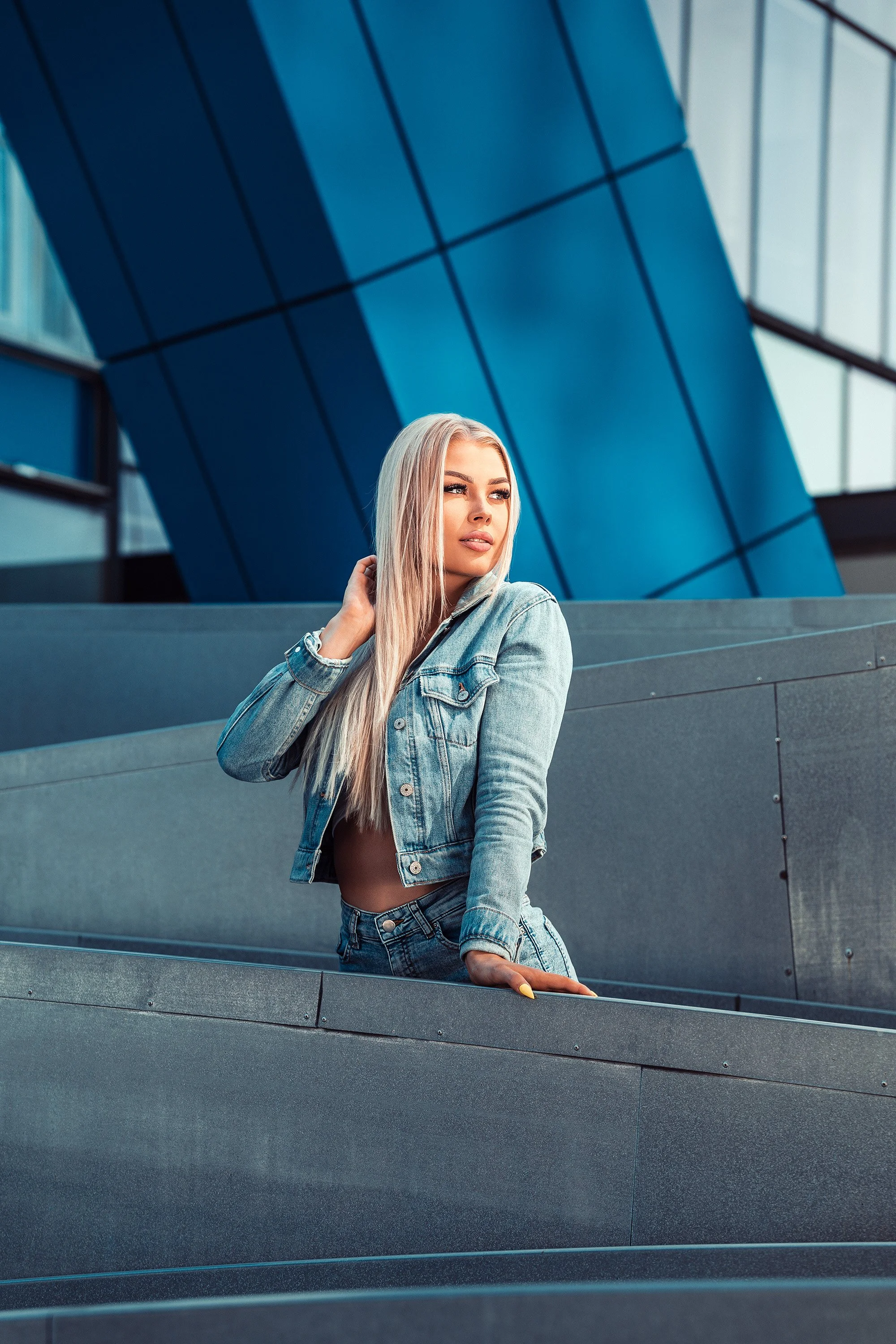 Julia Heikkinen poseeraa kuvan poikki kulkevien linjojen muodostamassa sommitelmassa HTC-talojen edessä. Muotokuvaus Helsinki – hyvän mielen valokuvaaja Sami Turunen.