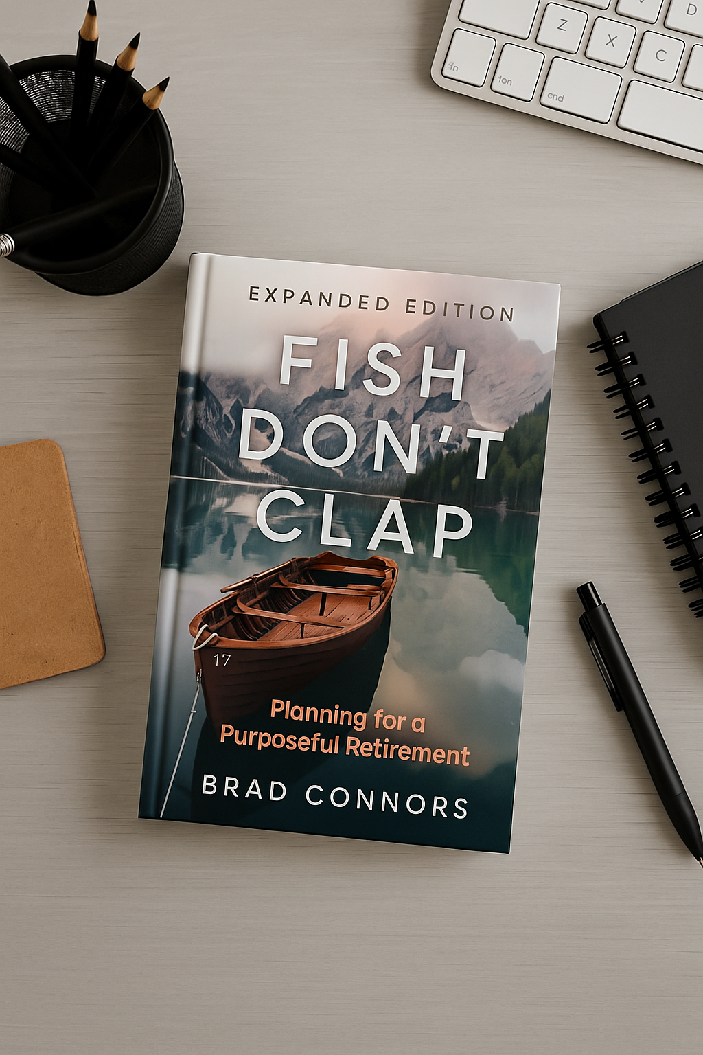 Book titled 'FISH DON'T CLAP' resting on a desk, with a pen, notebook, keyboard, and pencil holder around it.